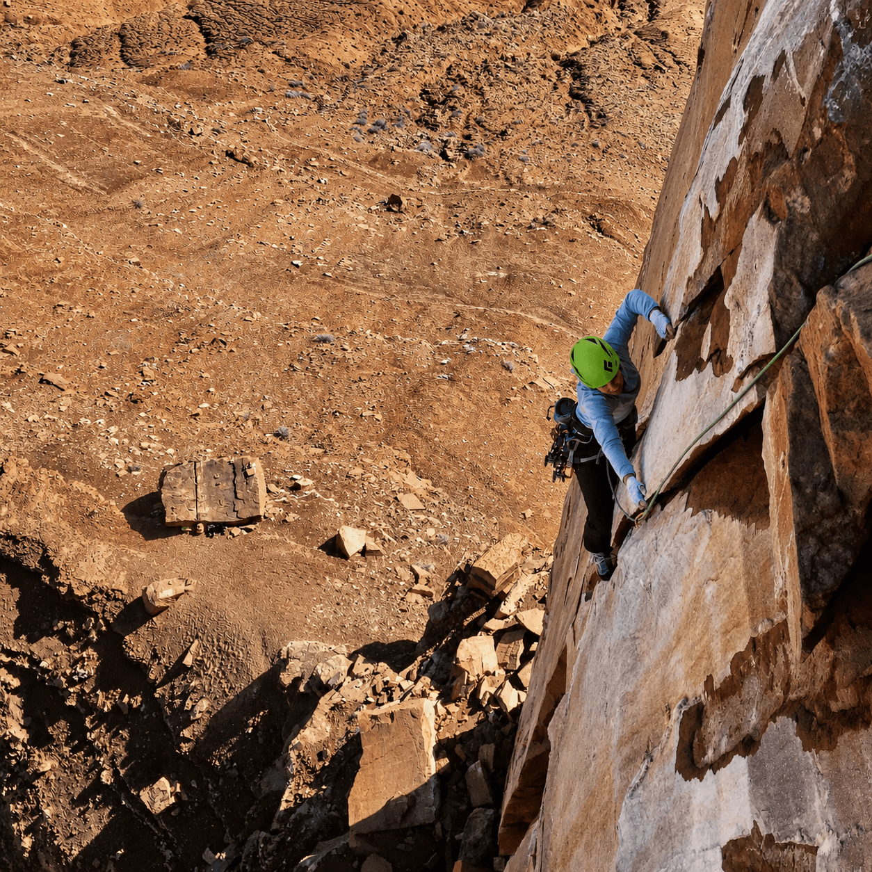 A climber in a green helmet is climbing the North Face of Casleton Tower outside of Moab.