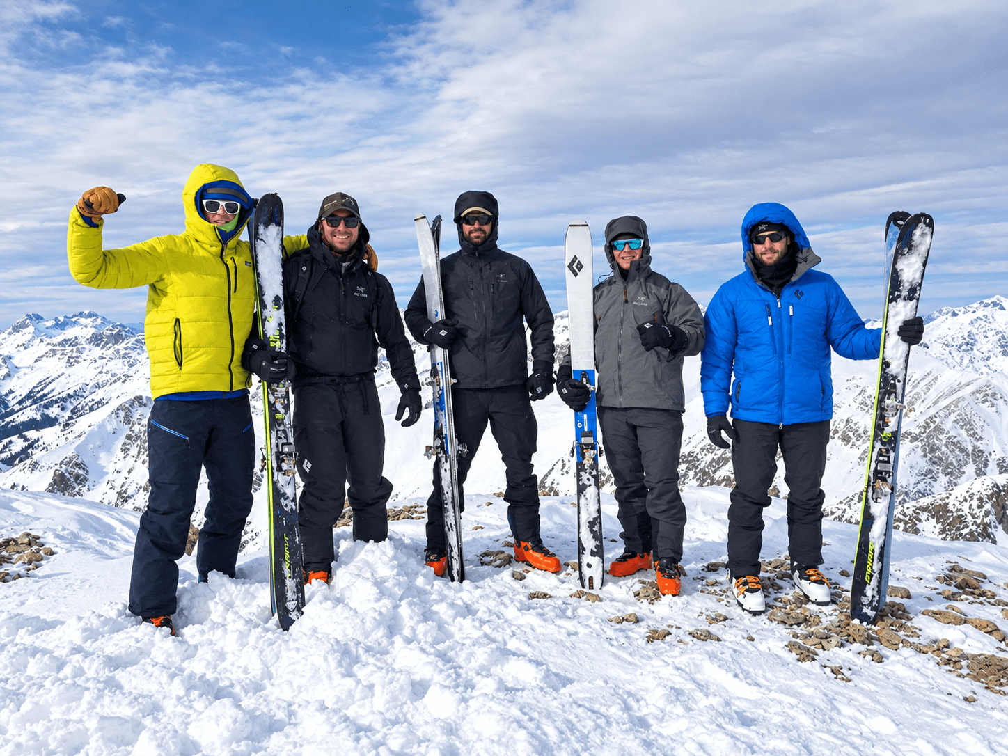A group of skiers celebrate on the summit of a peak during an Intro To Ski Alpinism course in Colorado.