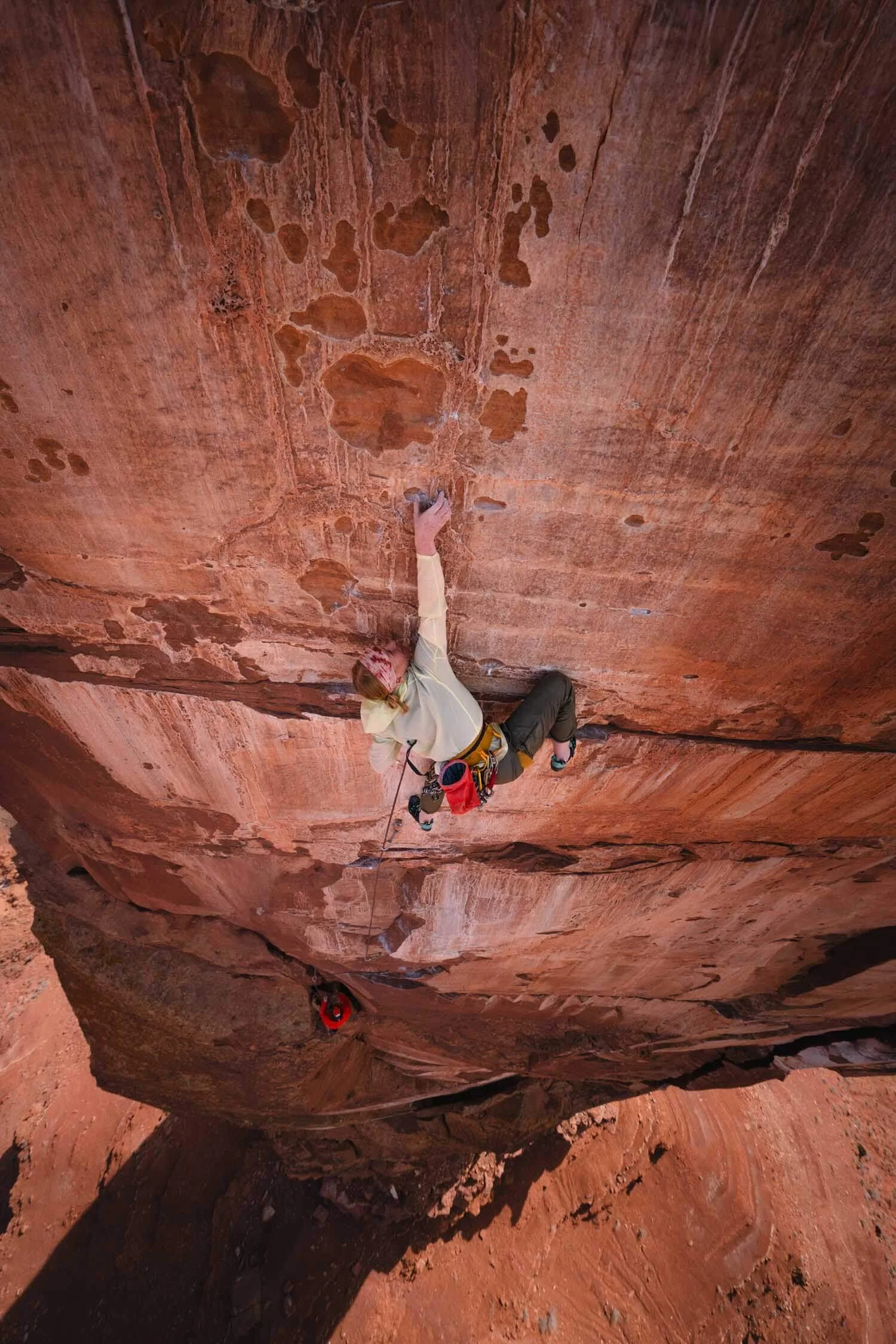 Skyward Mountaineering guide, Carly Casternovia is leading a rock climbing pitch on Castleton Tower. She is reaching up for the next hold on a steep, red sandstone wall.