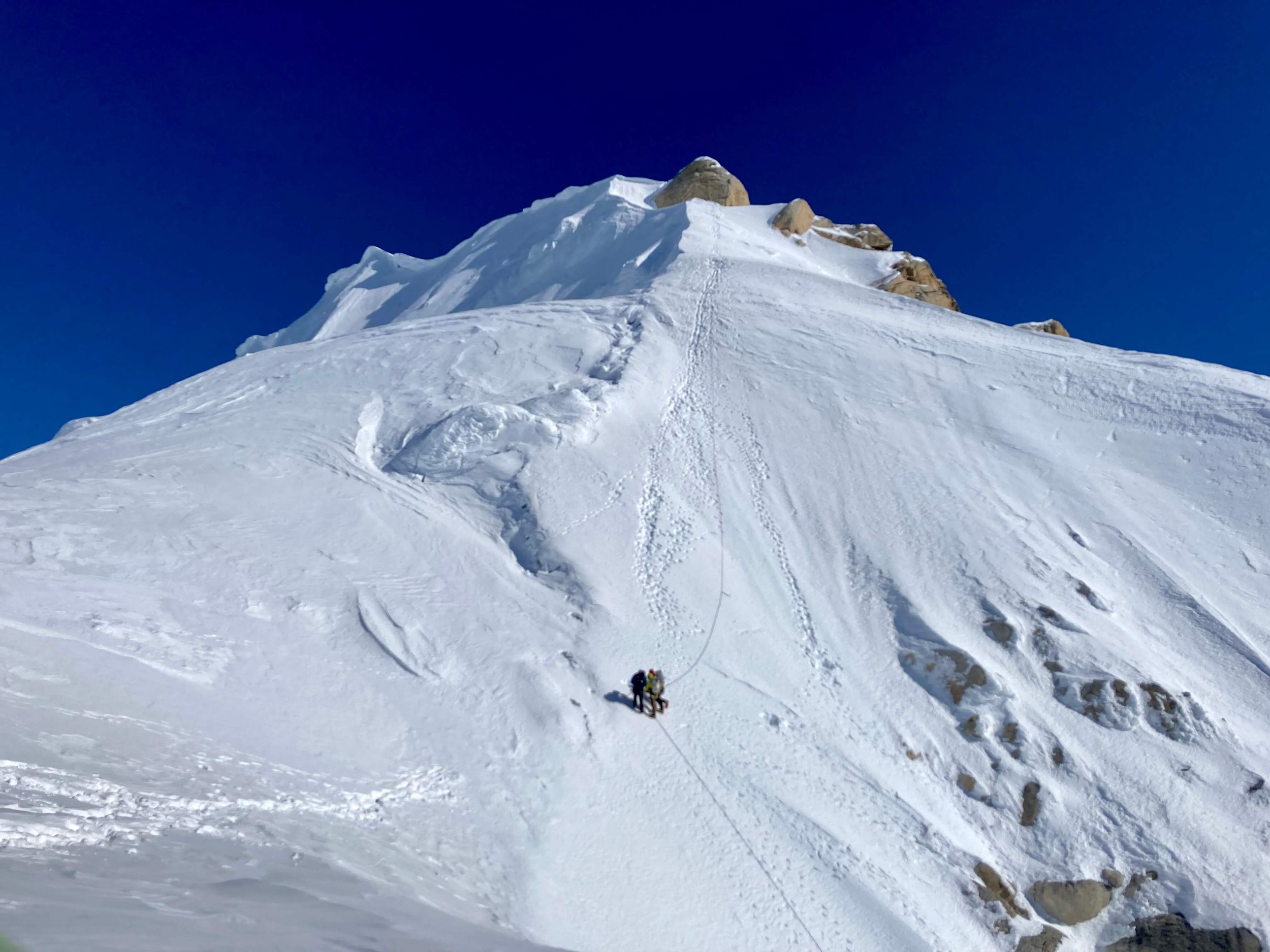 A team is rappelling from the summit of the Moose's Tooth into the Ham and Eggs couloir.