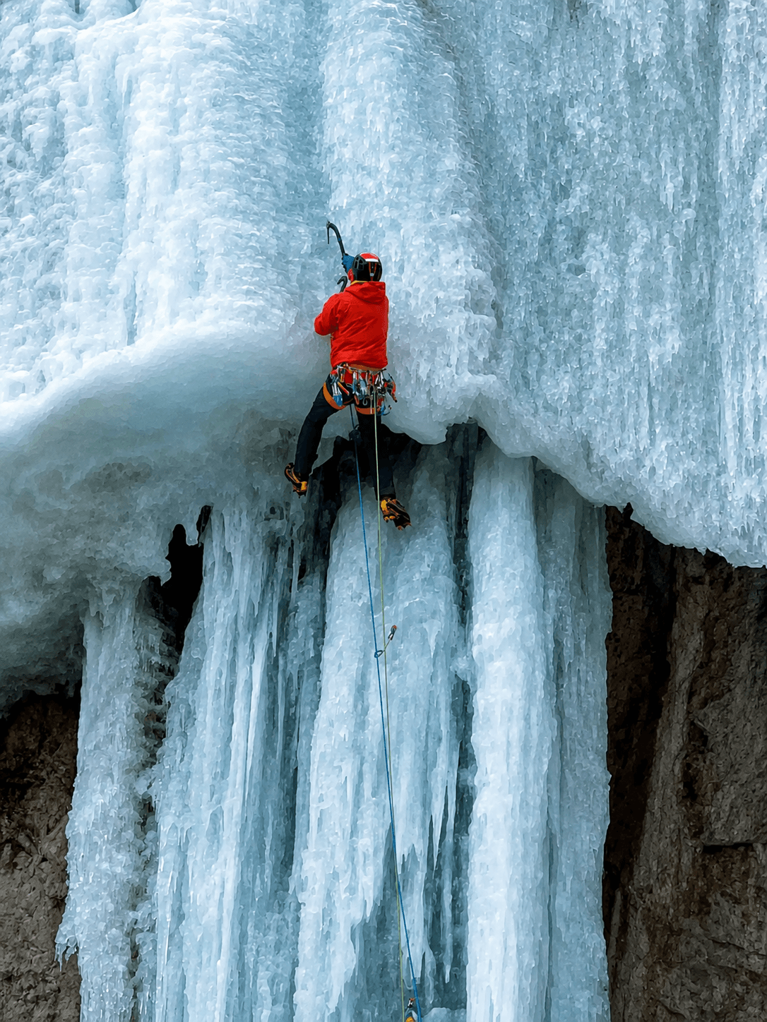 A guide leads a challenging route with a overhanging section during a steep ice climbing course.