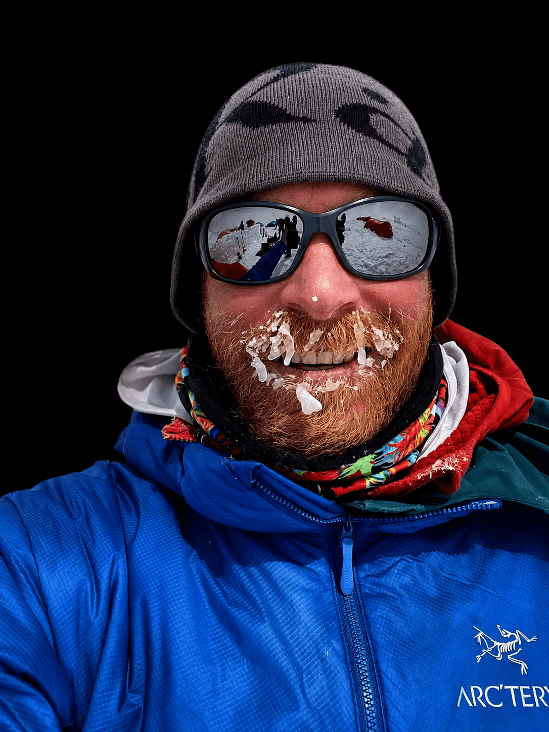 Skyward Mountaineering co-owner and guide, Micah Lewkowitz is smiling with a frozen beard when guiding an alpine climb in Alaska.