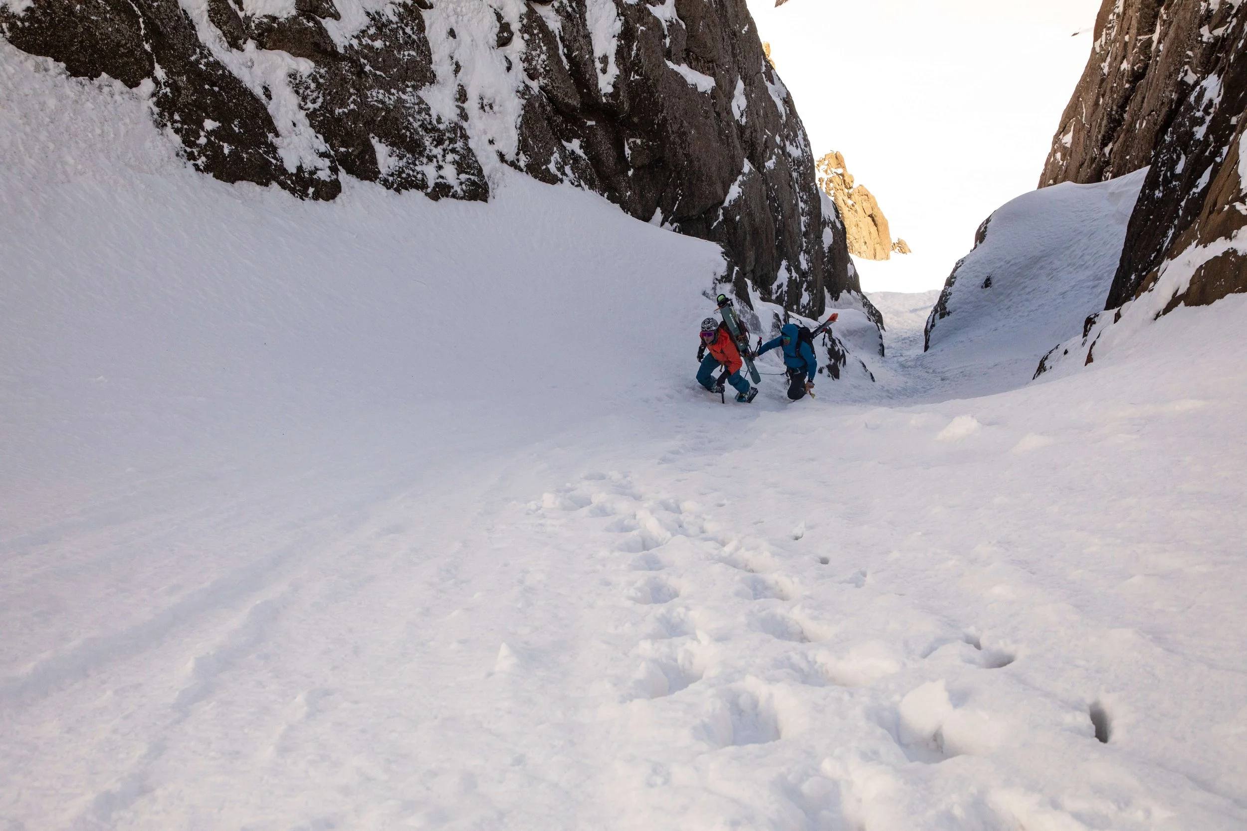 Skiers climb up a steep snow couloir in Silverton.