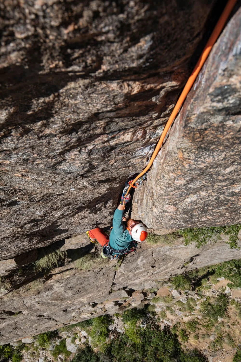 A climber in a blue shirt and red pants is climbing the finger crack crux of Midsummer Night's Dream in the Black Canyon.