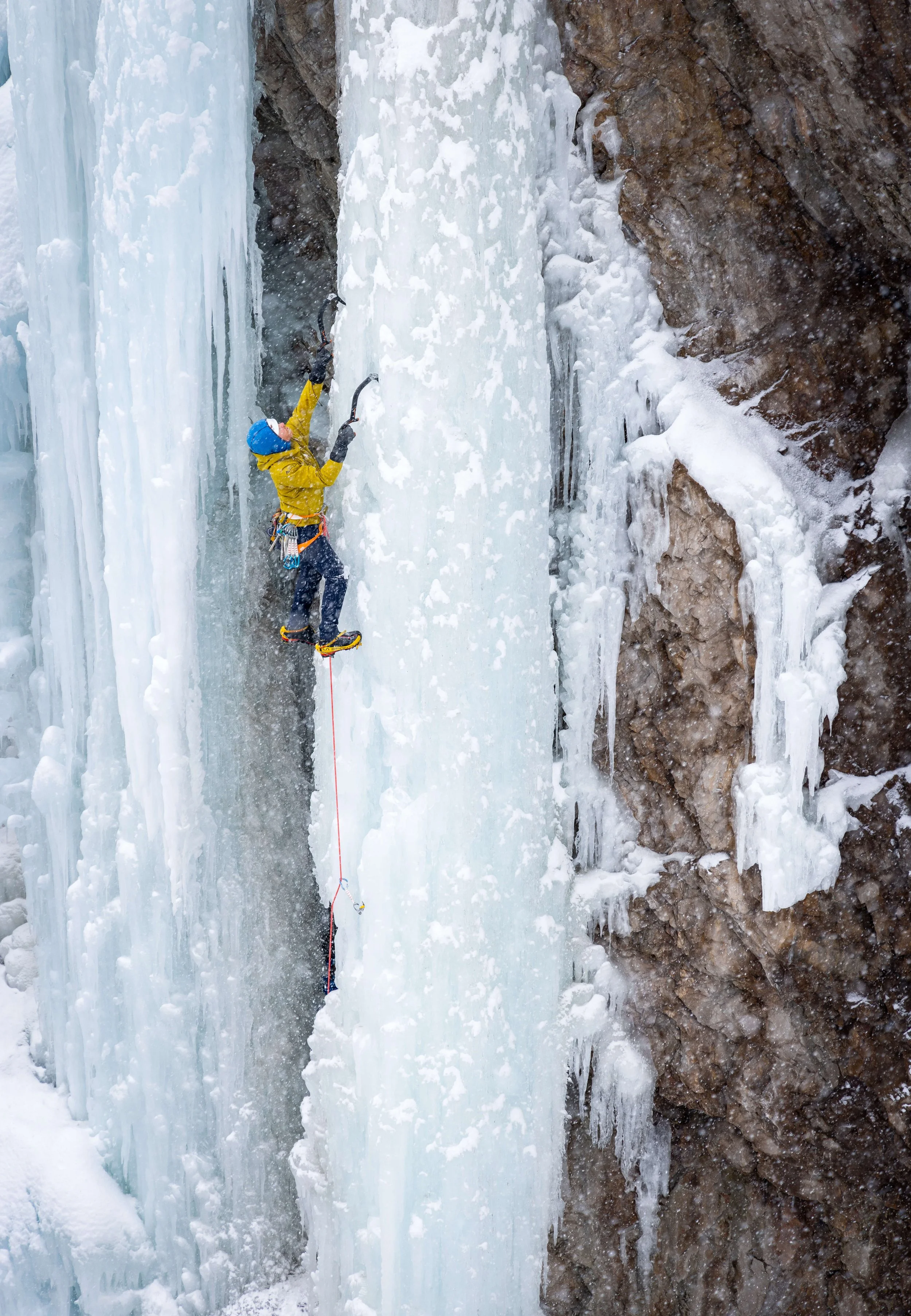 A guide in a yellow jacket is leading a steep ice climbing route in the Ouray Ice Park.