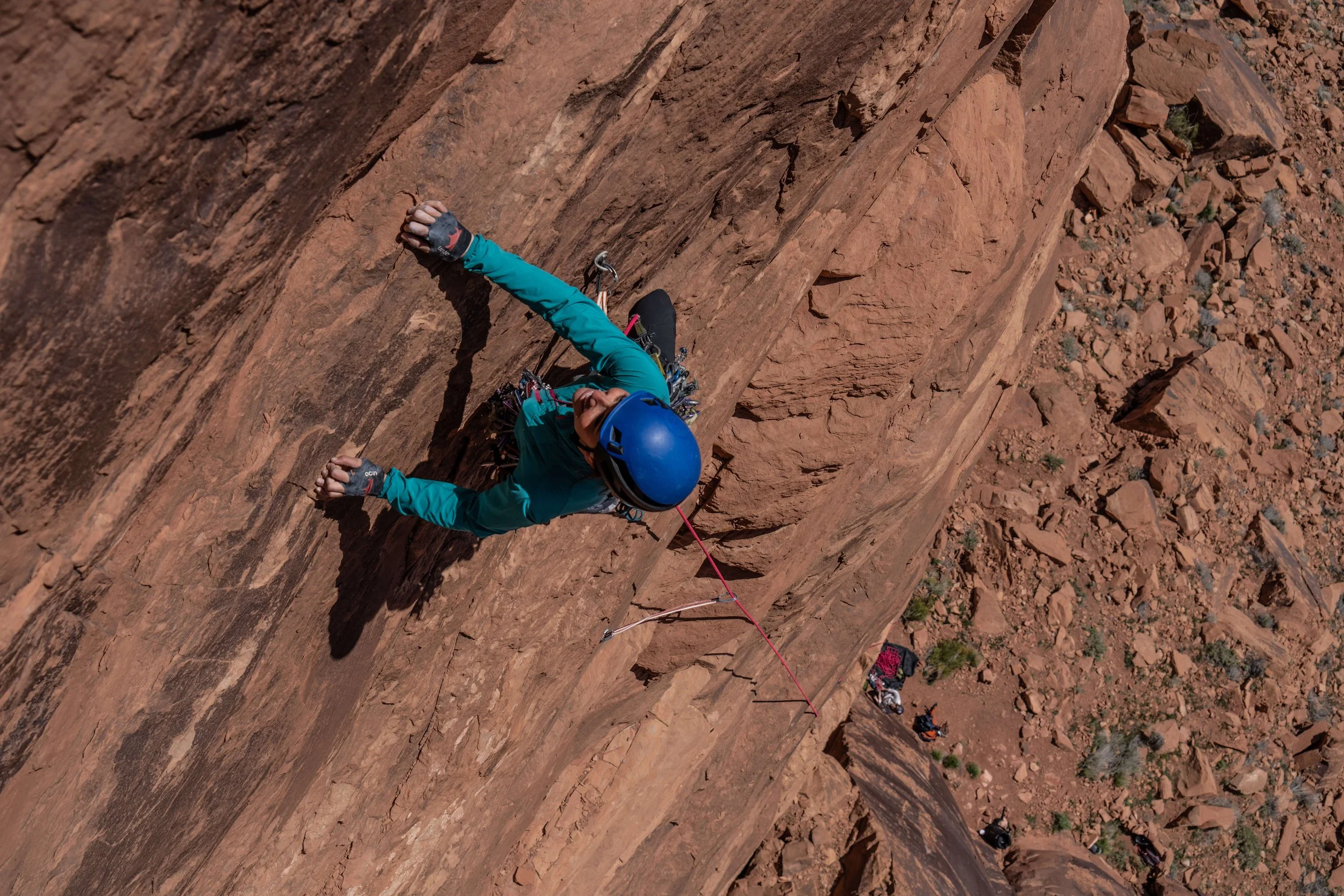 A woman in a blue shirt is leading the multipitch route Terma at Big Bend in Moab, Utah.
