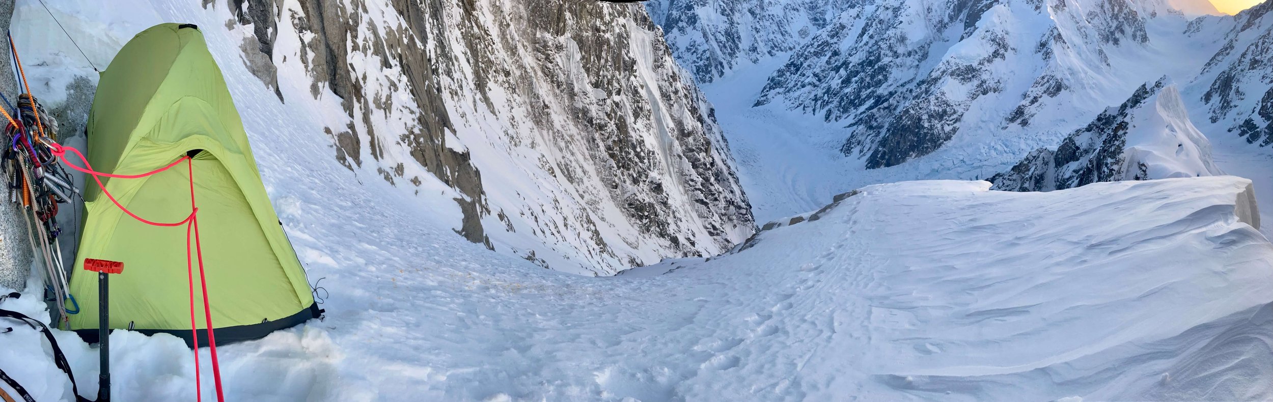 A tent perched on a small bivy ledge.