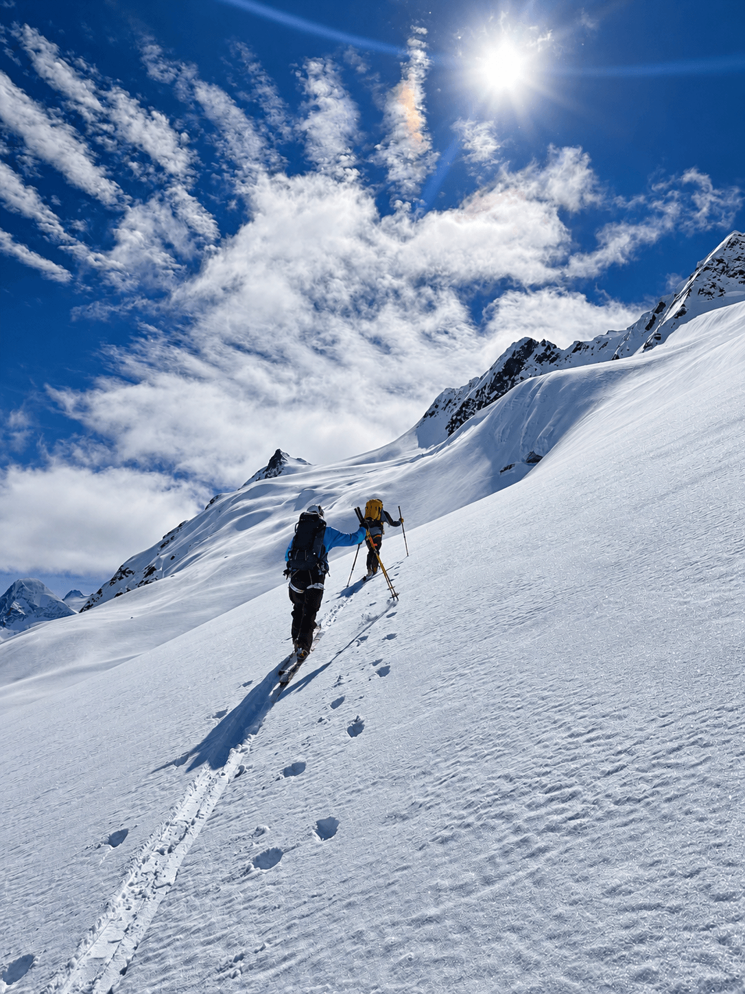 Two skiers climb up a steep glacier.