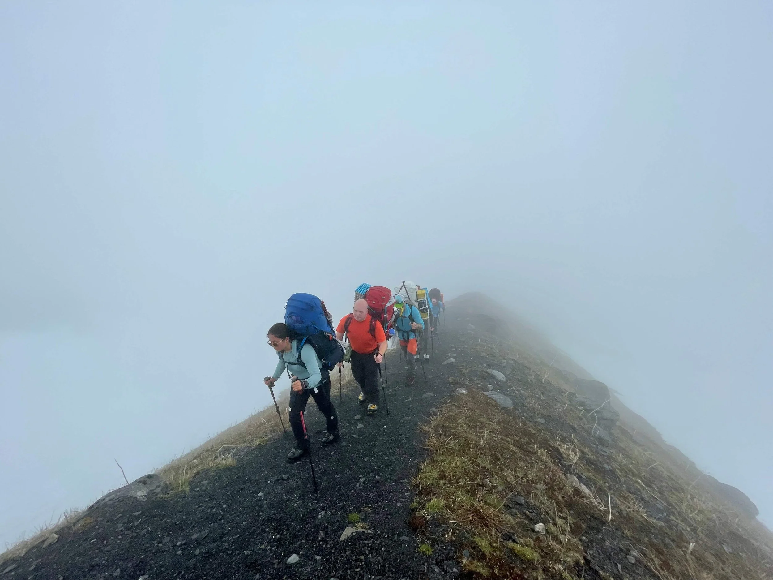 A group of climbers hike up the Heliotrope Ridge trail on Mount Baker during a foggy day.