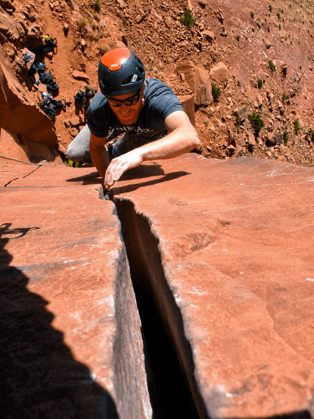 A guide leads a crack climbing route in Escalante Canyon, jamming his hands in the crack.