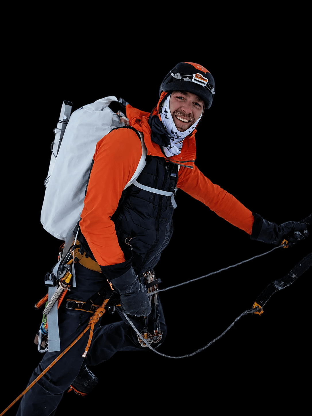 Skyward Mountaineering guide, John Collis. He is wearing an orange and blue jacket with a white backpack during an alpine climb in Alaska.