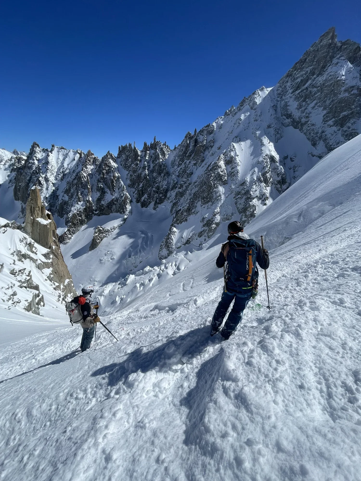Two skiers look at the track down a snowy glacier in the French Alps.