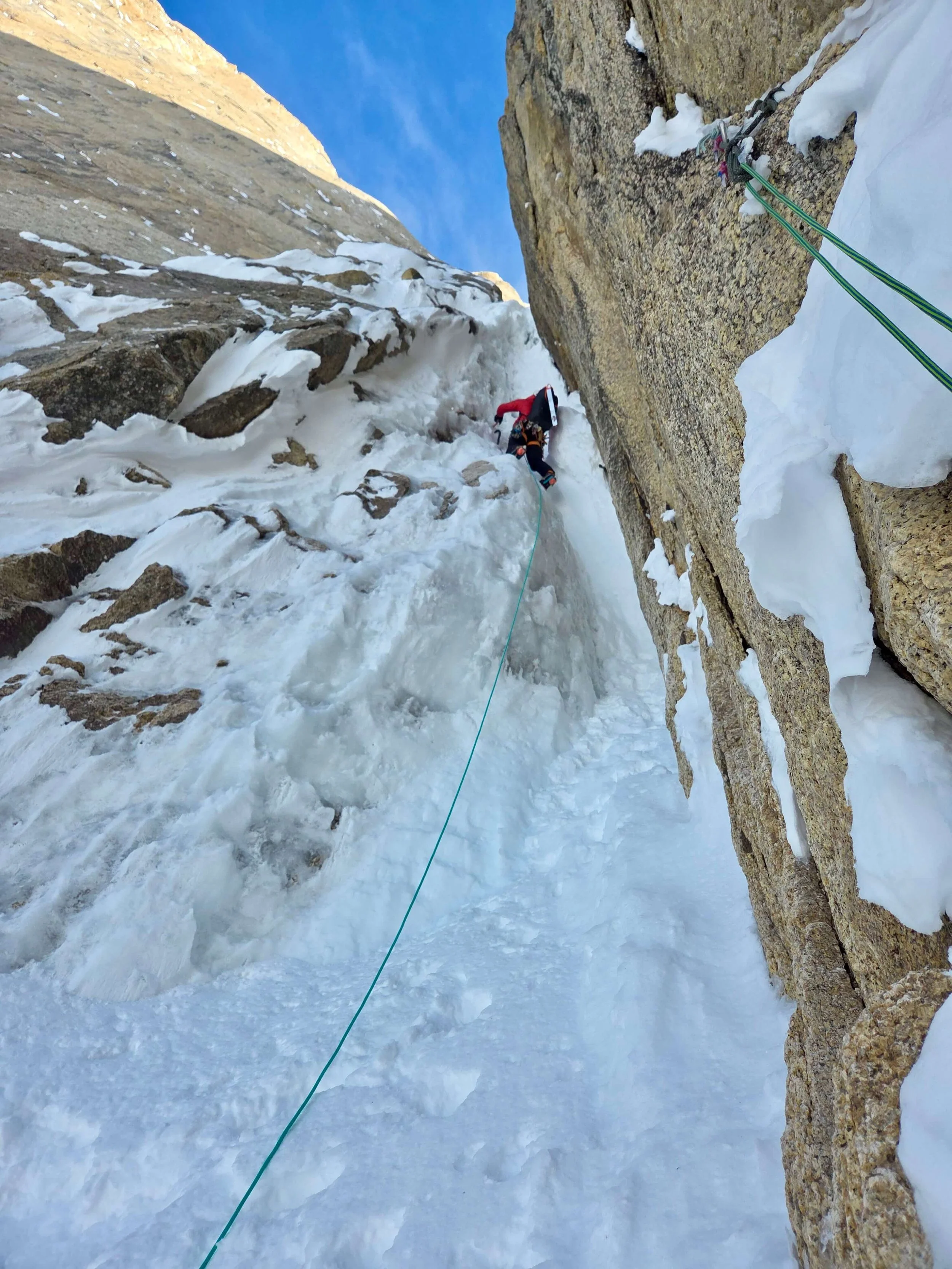 A Skyward Mountaineering guide is leading a crux ice climbing pitch on Ham and Eggs. A blue rope trails below him to the belayer.