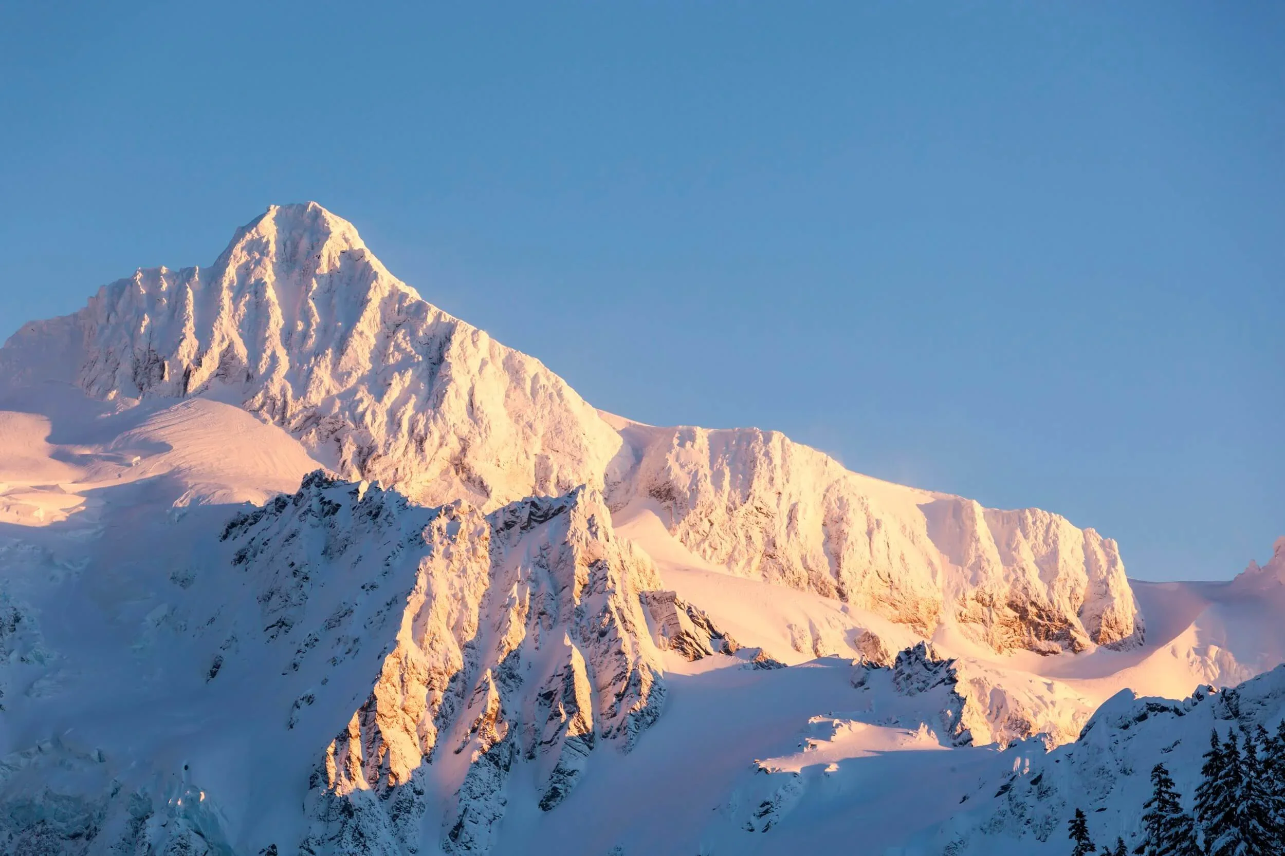 A snowy summit pyramid during midwinter on Mount Shuksan with the Hanging Glacier and White Salmon Glacier below.