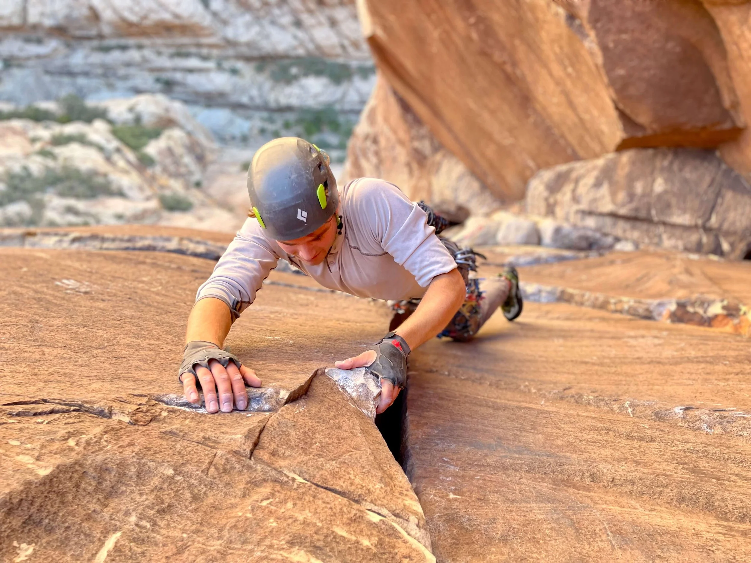 A climber wearing a gray shirt and helmet is leading the route Epinephrine in Red Rock Canyon, Nevada.