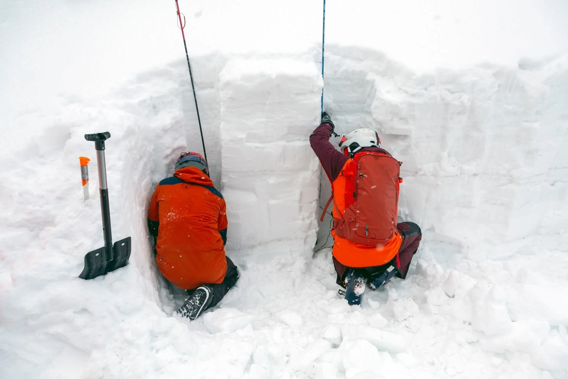 Two students on an an avalanche education course dig a snow pit and isolate a column to conduct a stability test.