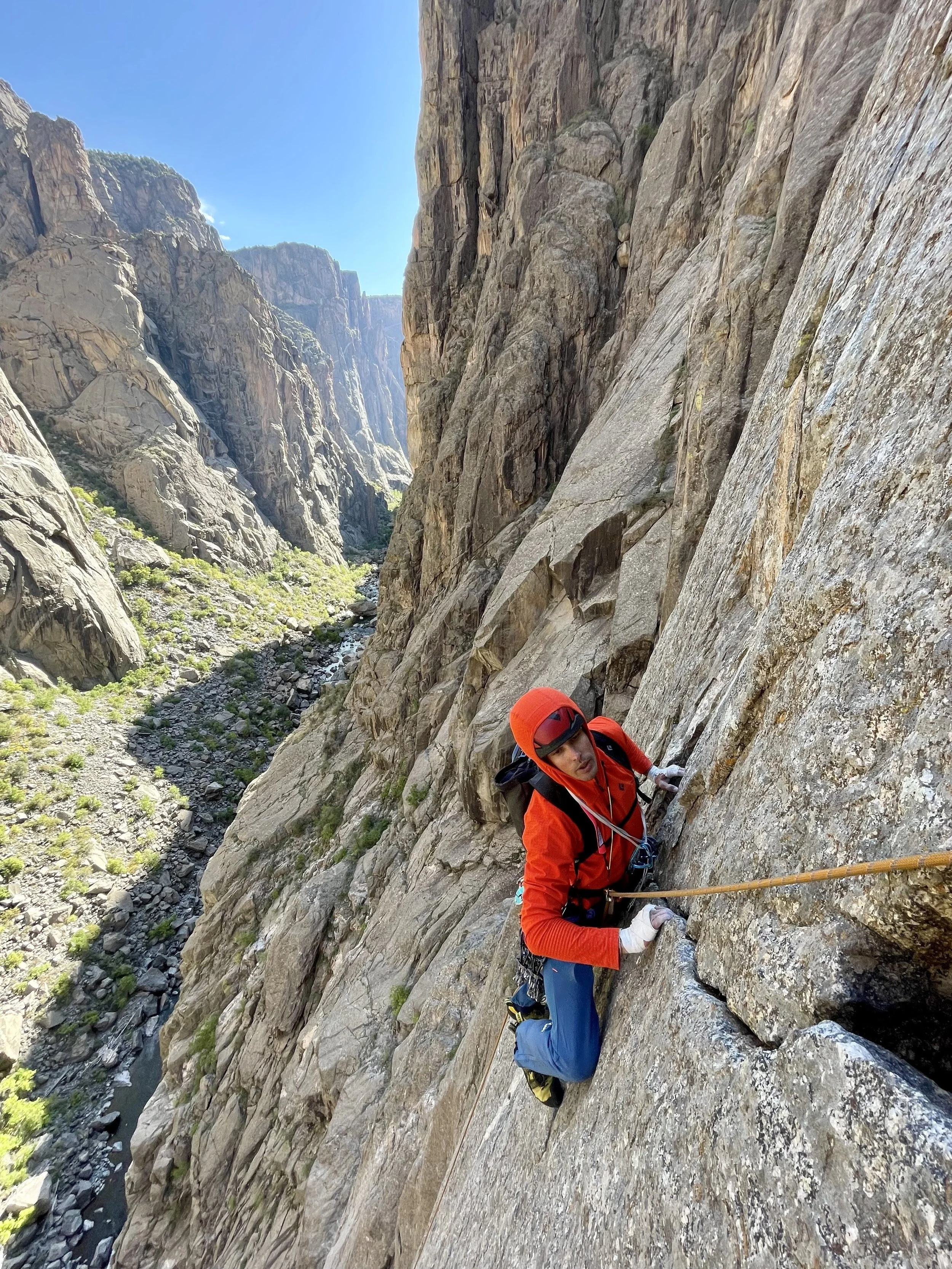 A climber is following a finger crack pitch on the classic route, Astro Dog on the South Rim of the Black Canyon.