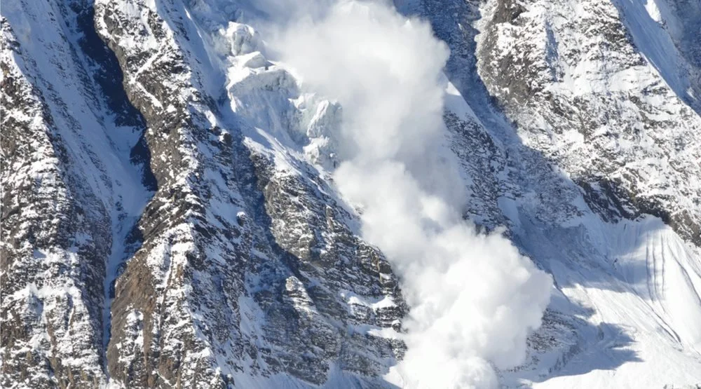 A large avalanche is viewed going over an ice climbing route in Canada.