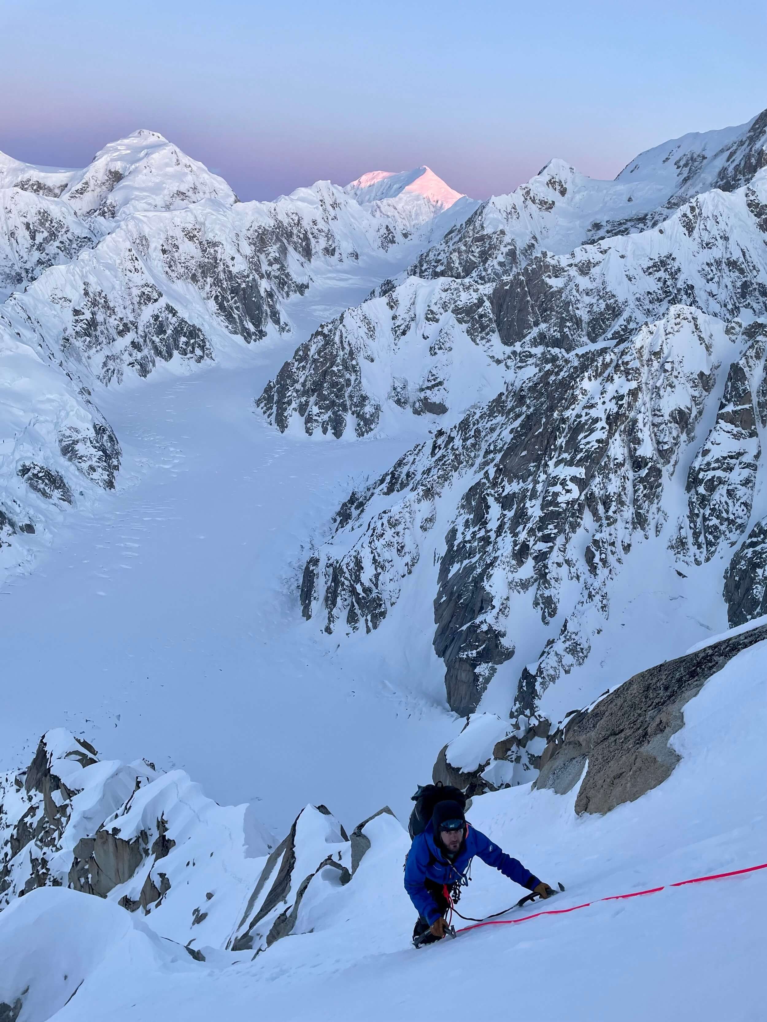 Climbing the final headwall to the summit of Peak 11,300 with sunrise alpenglow lighting up the West Fork in the background.