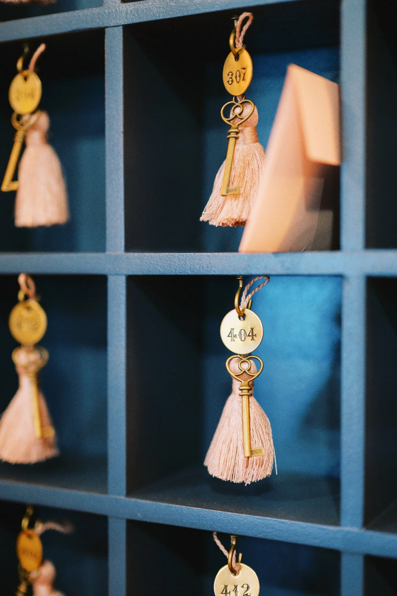Blue mailbox with numbered key tags, tassels, and small paper notes inside compartments.