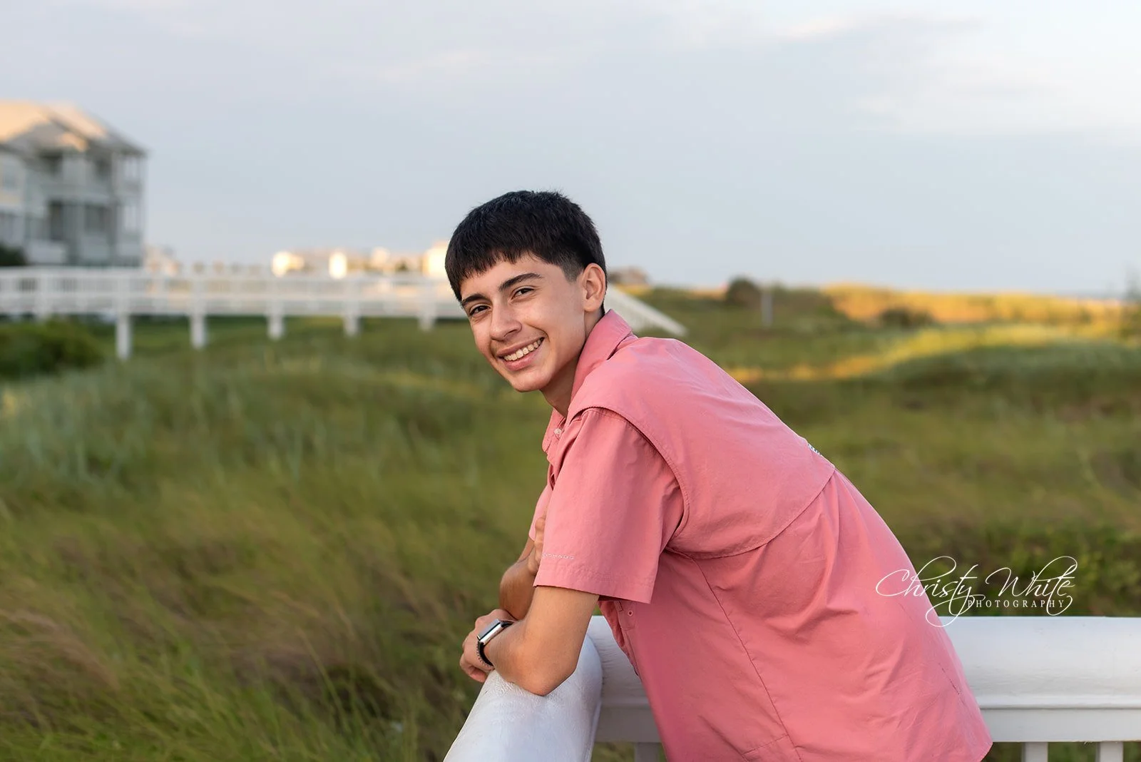 Class of 2027 senior portrait near the white boardwalk and beach houses in Galveston Beach Town