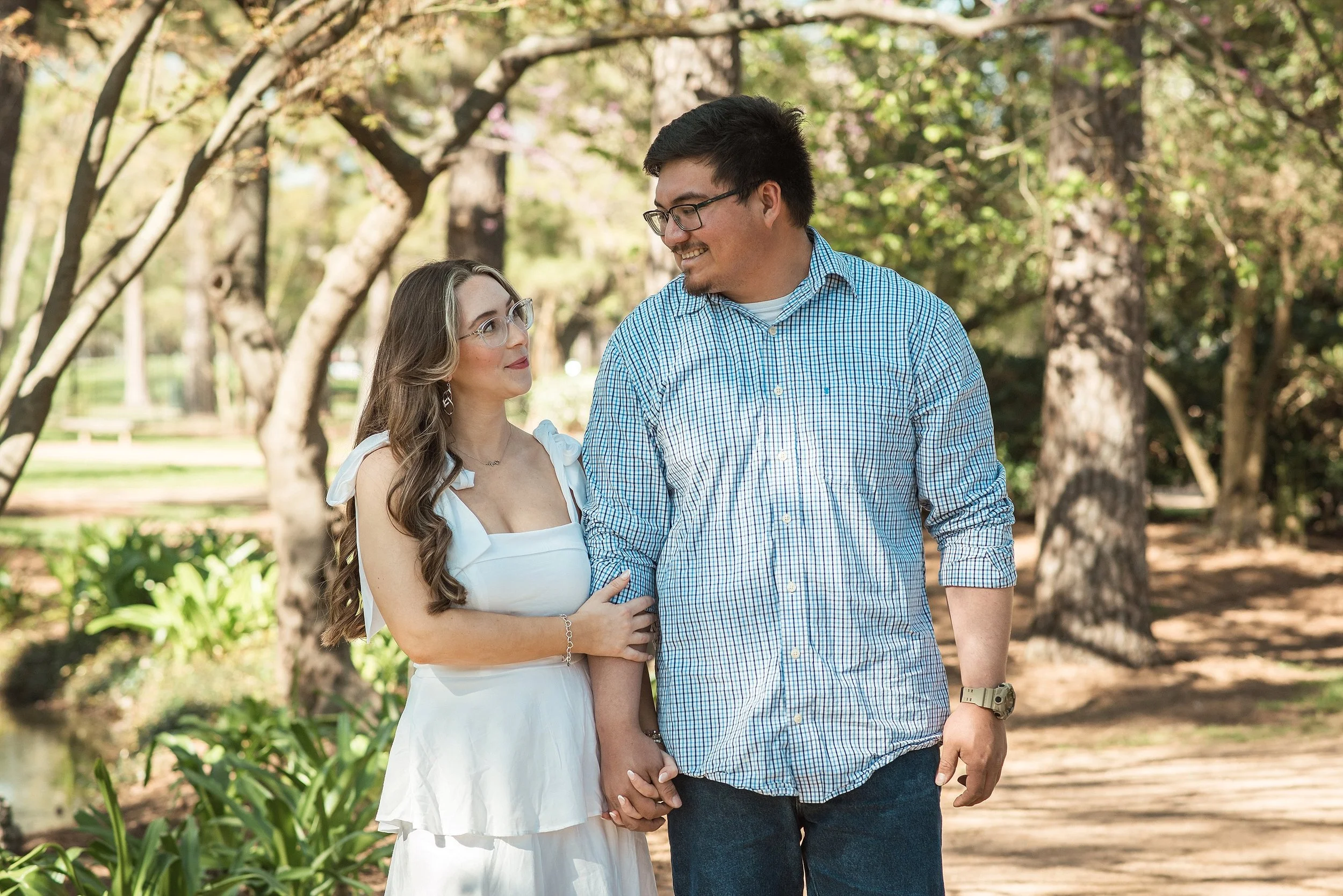 Couple walking under trees at Hermann Park in Houston during a spring engagement session