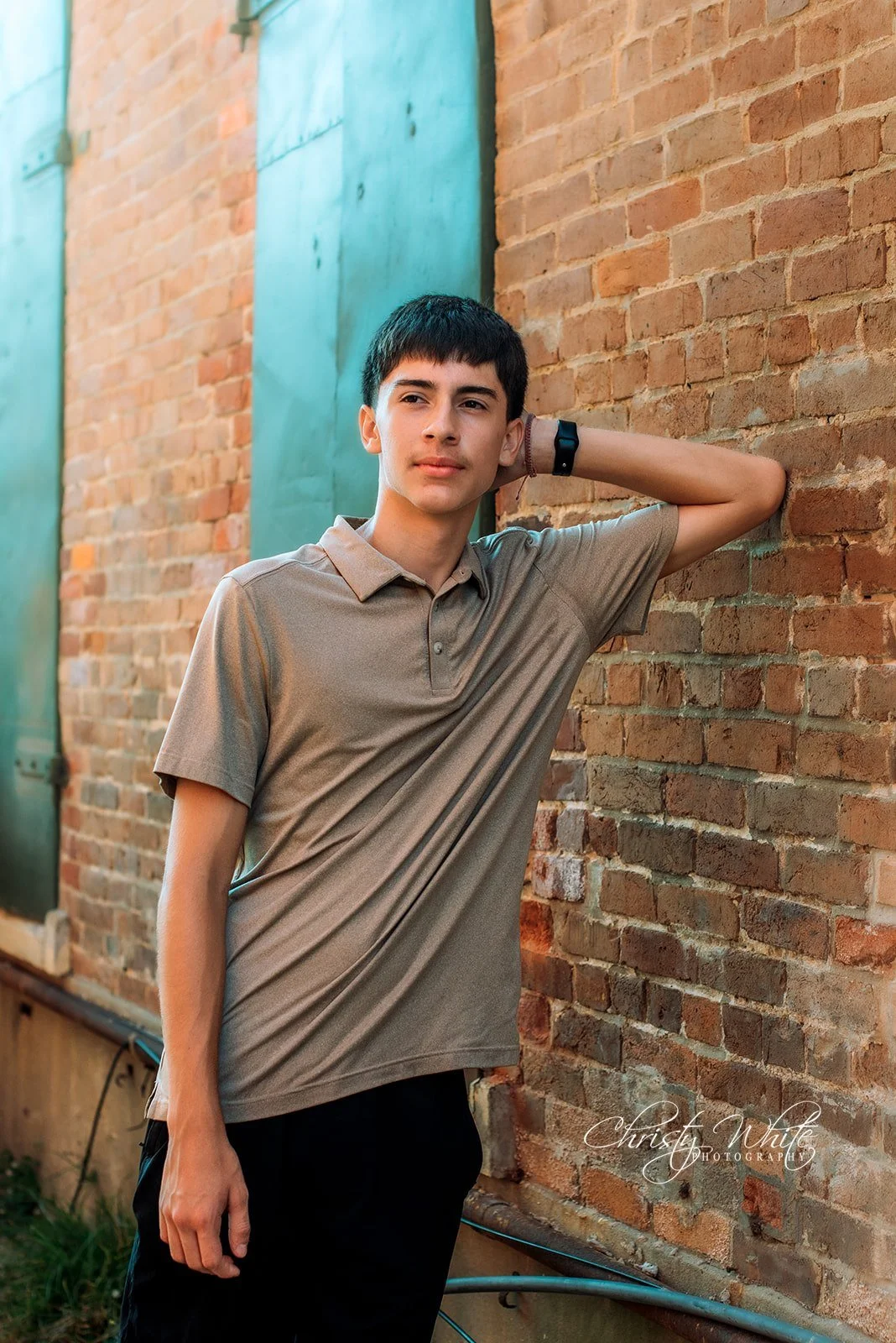 Senior leaning against a wall with golden sun flare during his Galveston Strand senior session