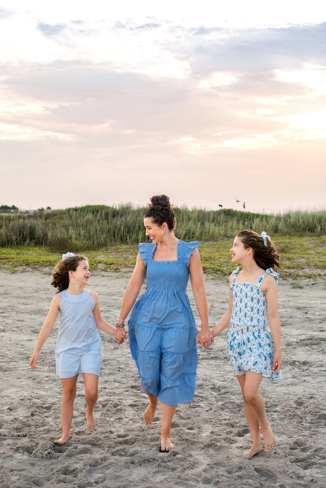A mom and her daughters walking along a Gulf Coast Beach.