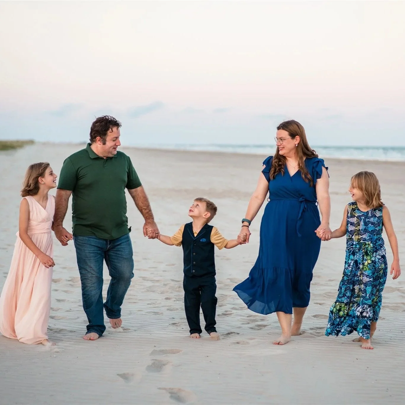 Family walking along shoreline during relaxed natural sunset family photography session in Galveston Texas