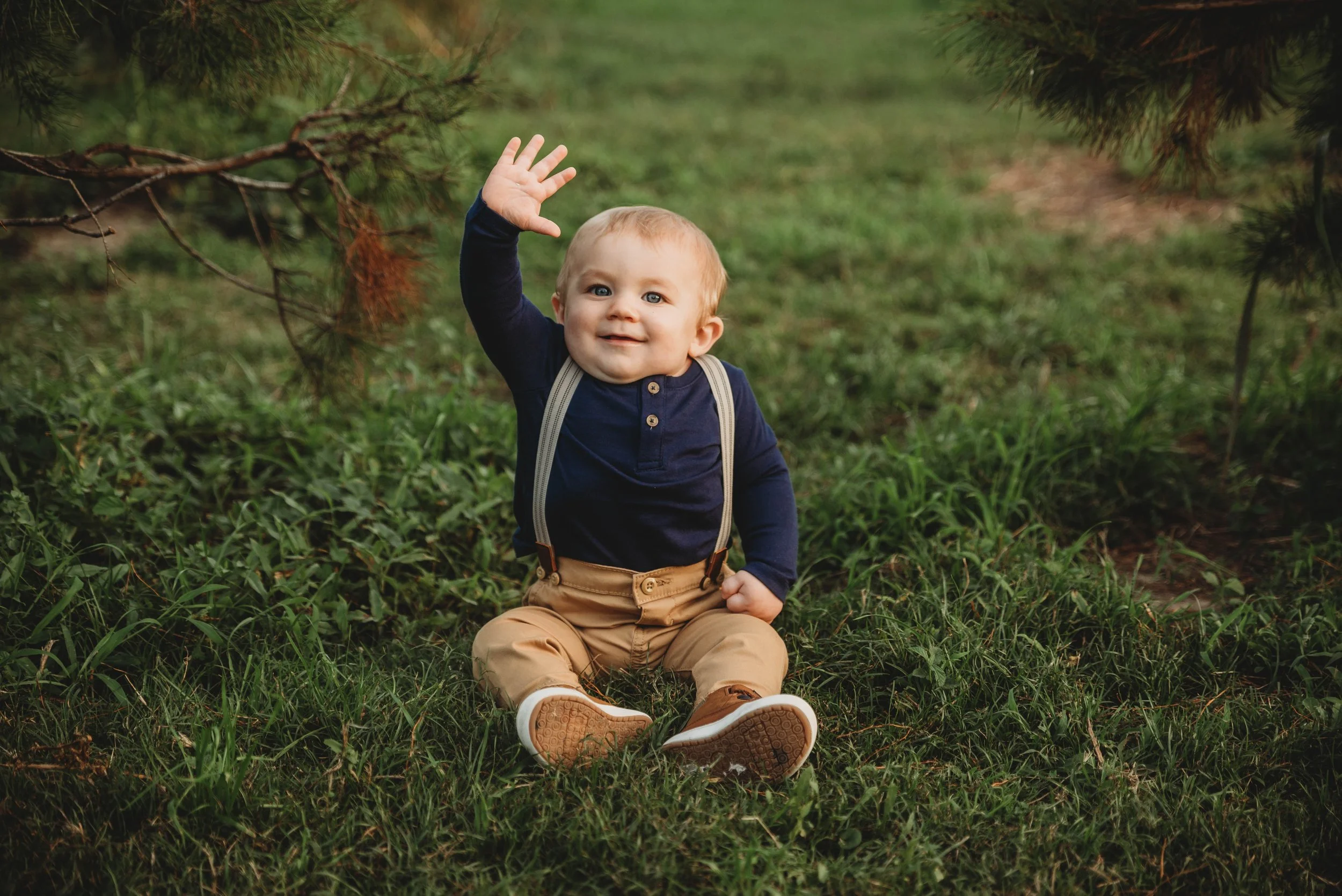 Curious toddler waving during a stress-free outdoor mini session in Alvin, Texas.