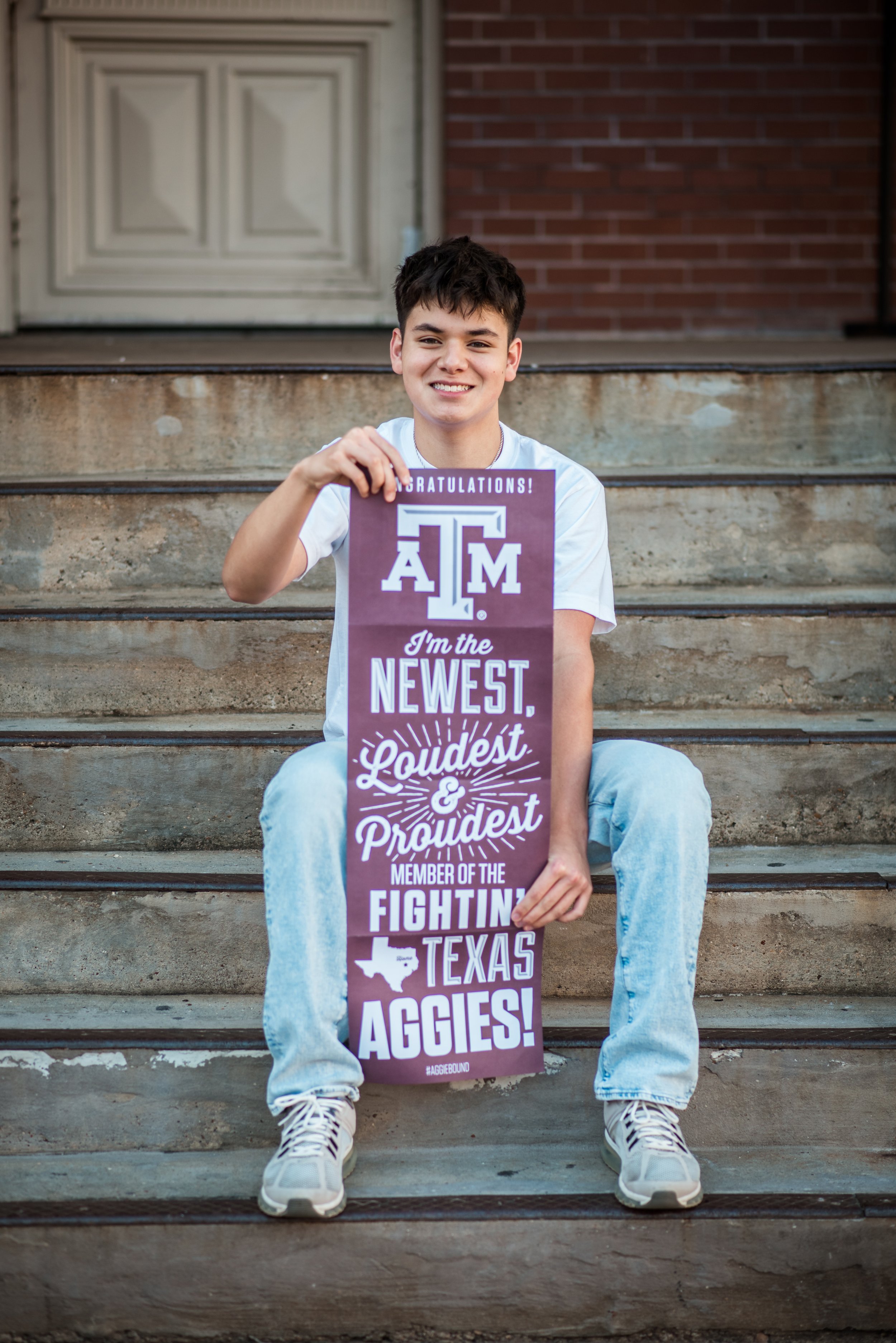 A high school senior showing off his acceptance banner to college