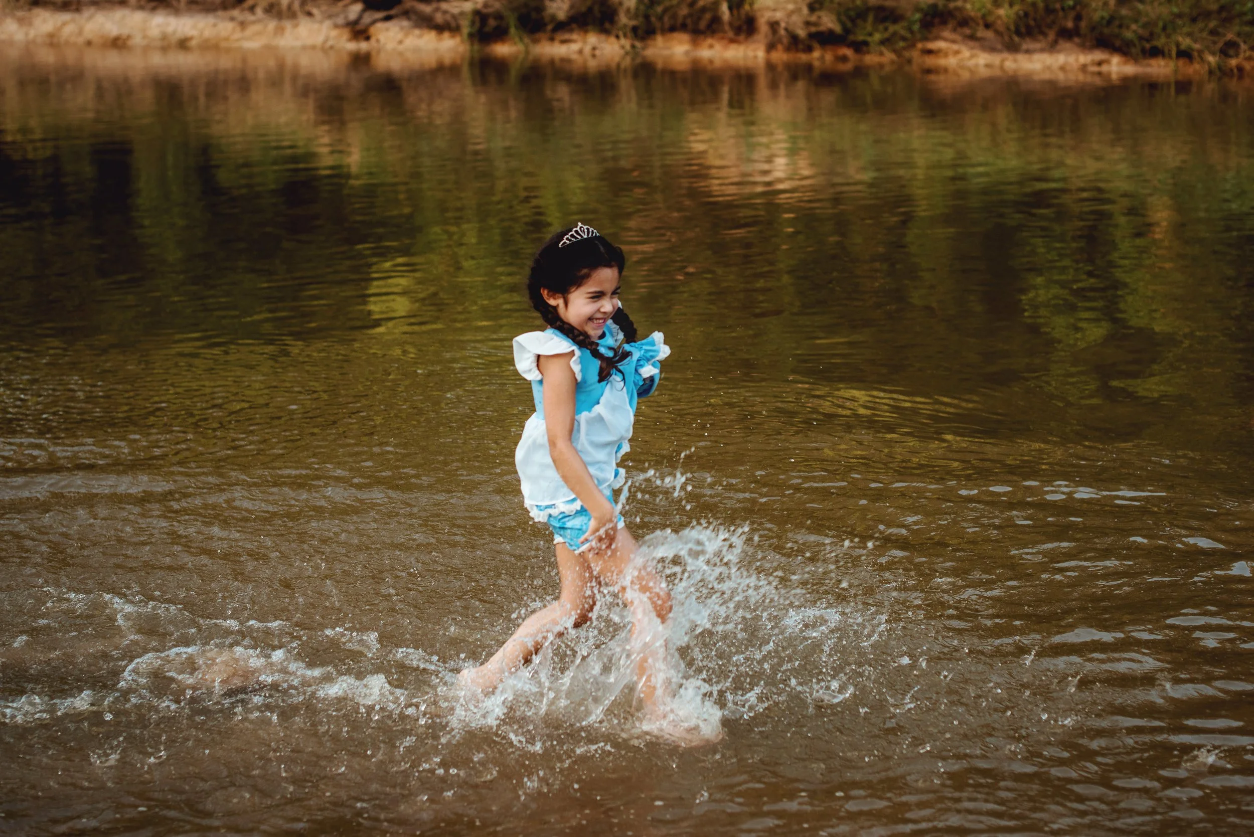 Children laughing while splashing through the creek during an outdoor family photography session in Spring, Texas.