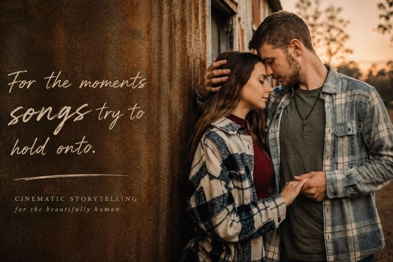 A man and woman stand close against an old rusted wall, touching foreheads and holding hands, with a sunset sky in the background, evoking intimacy and connection.
