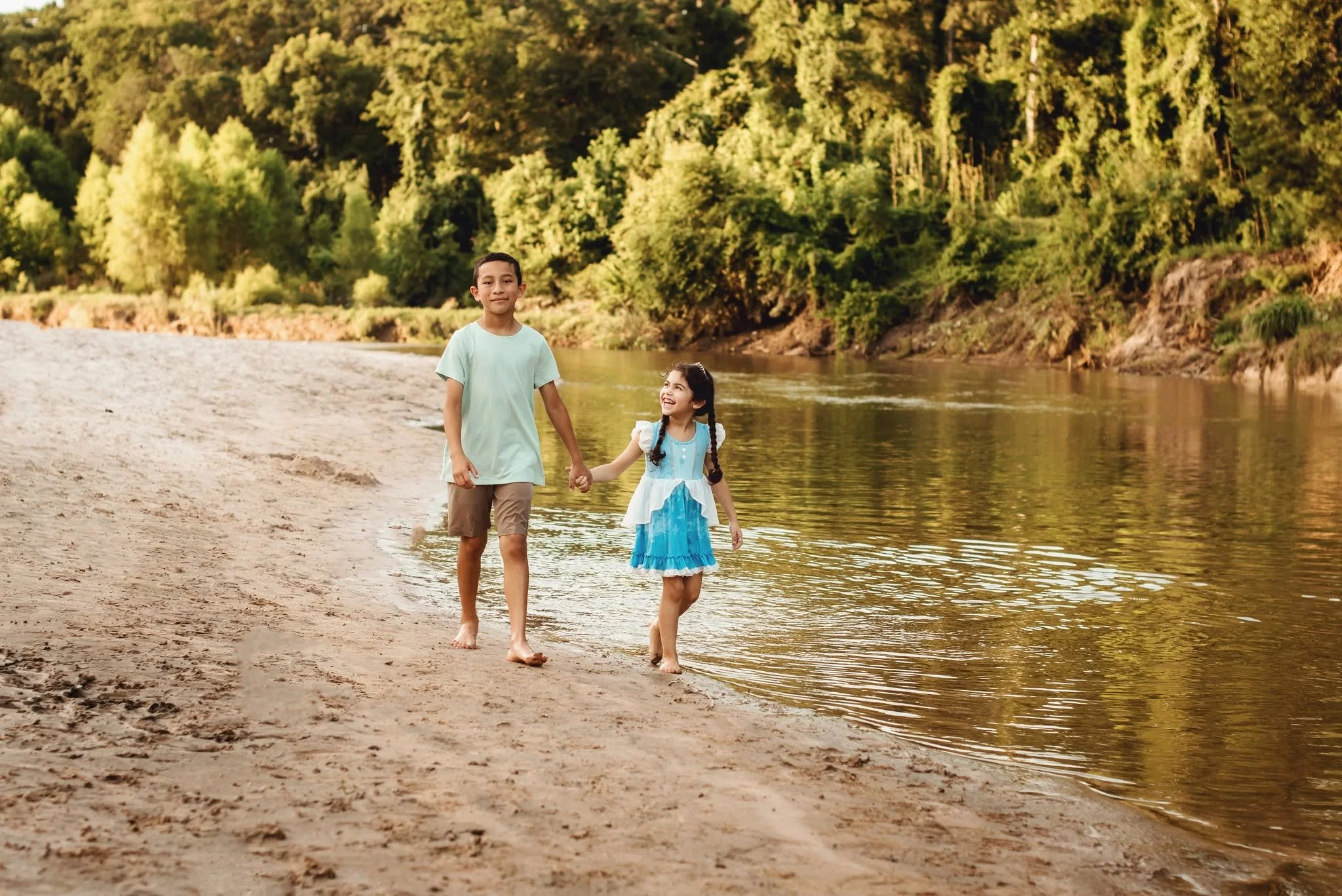 Little girl wearing a blue princess dress while exploring the creek during a storytelling family photography session.