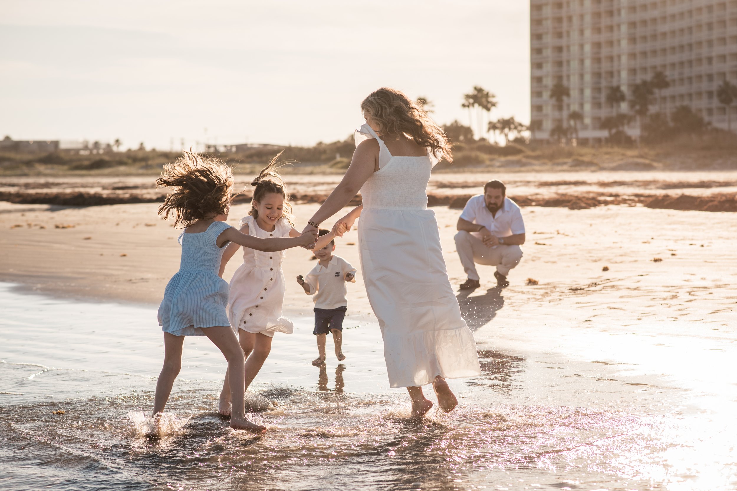 A family has fun playing on a beach during a photography session in Galveston