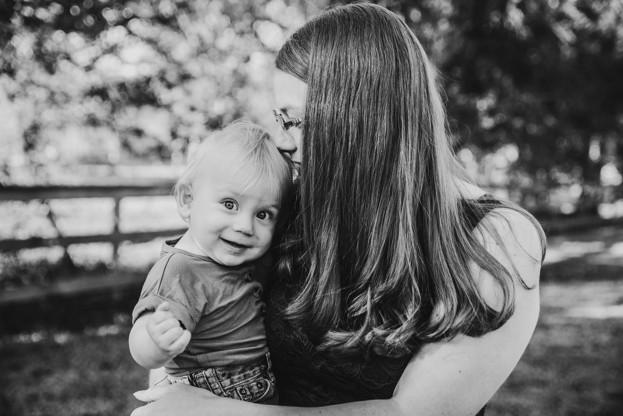 Parent holding a happy toddler during a relaxed outdoor family photo session near Angleton, Texas.