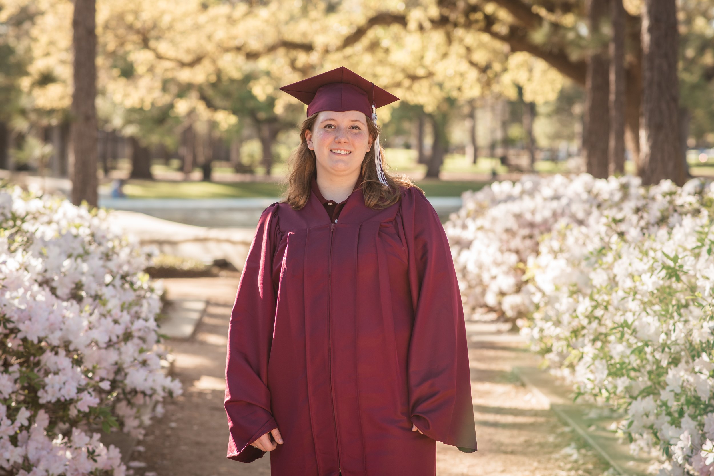 A Pearland High school senior in cap and gown surrounded by flowers