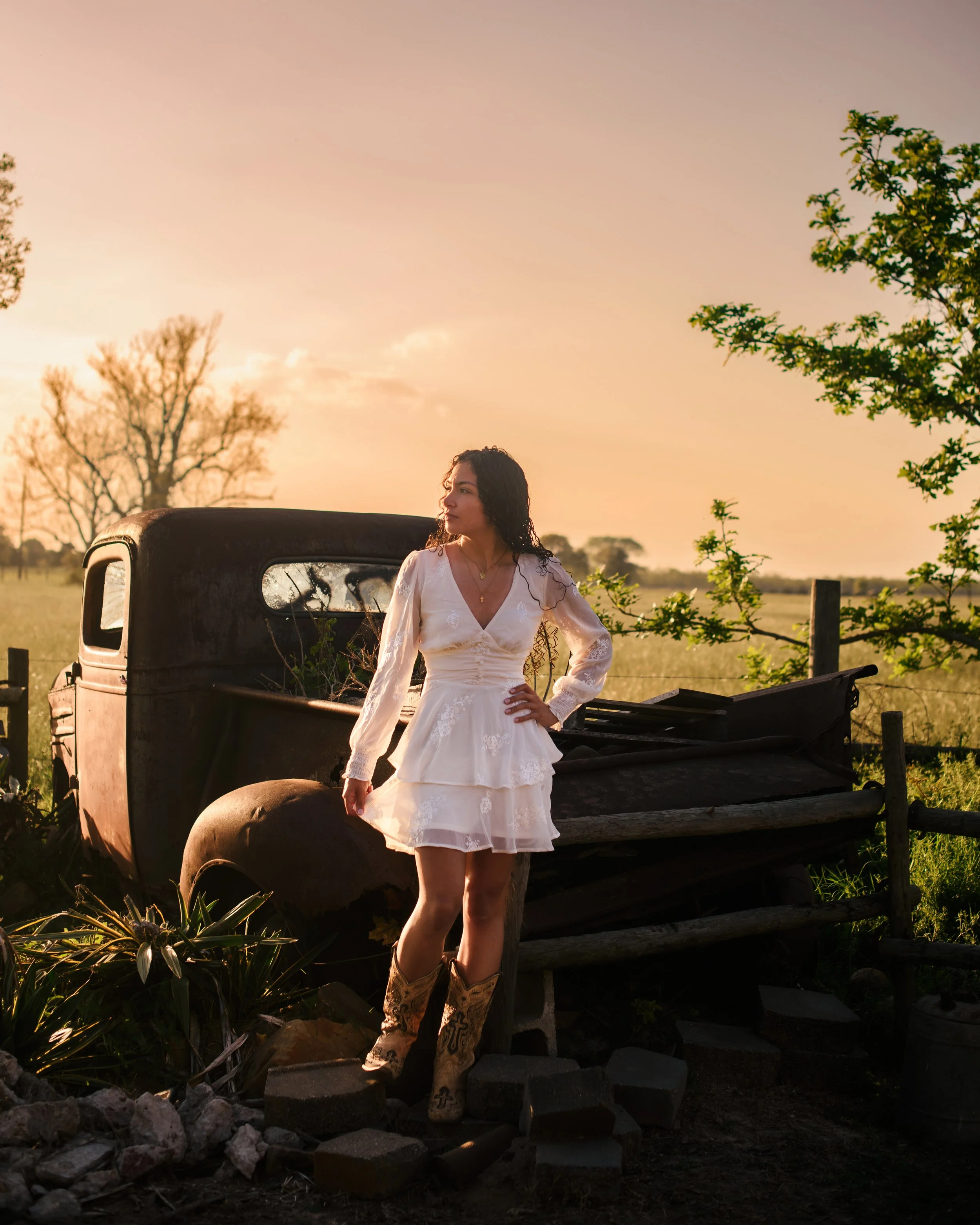 A Texas High School Senior standing by an old truck at sunset