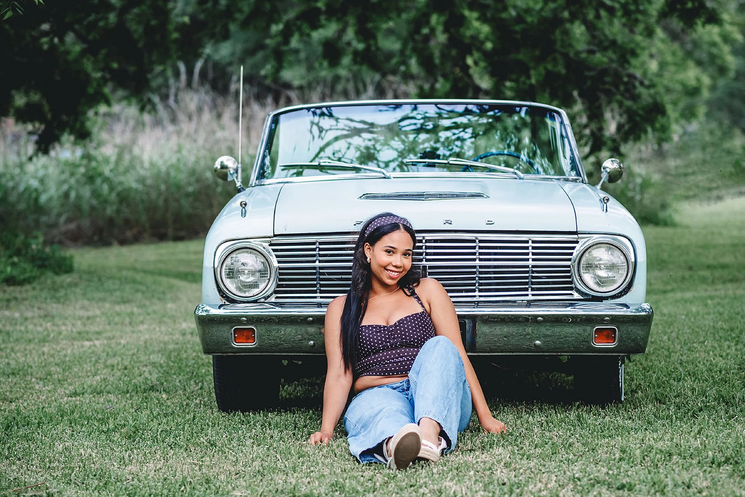 High school senior sitting in front of a blue car