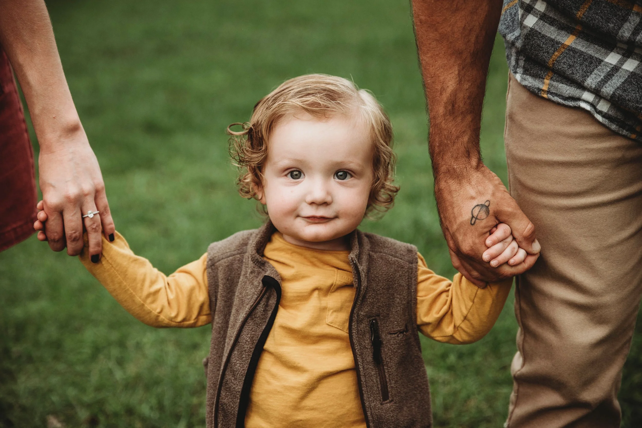 Family cuddling their toddler during a candid outdoor photography session serving Alvin and the Houston area.