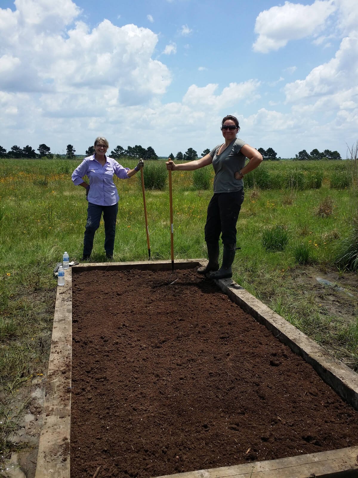 Two people building a garden bed in the prairie.