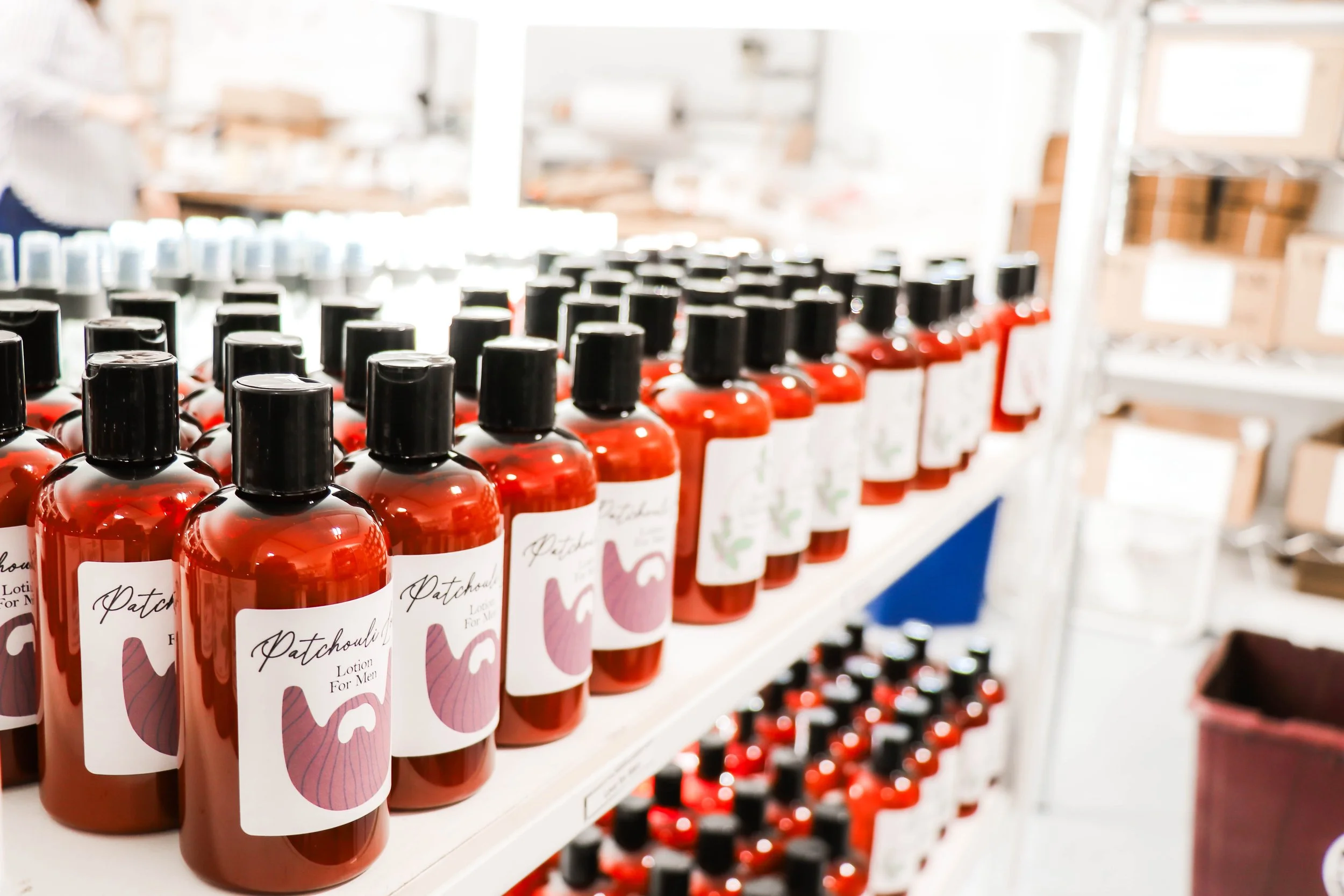 Shelves filled with bottles of Patchouli lotion for men, in a retail store.