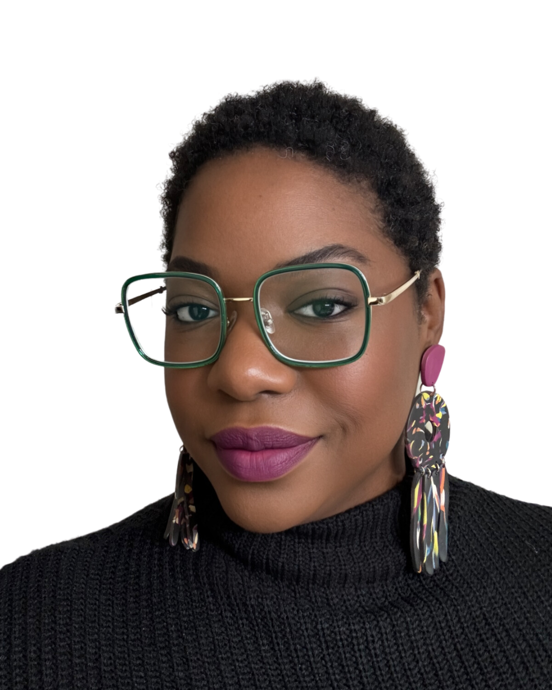 Close-up portrait of a woman with dark curly hair, wearing large green glasses, bold lipstick, and colorful earrings, against a plain white background.
