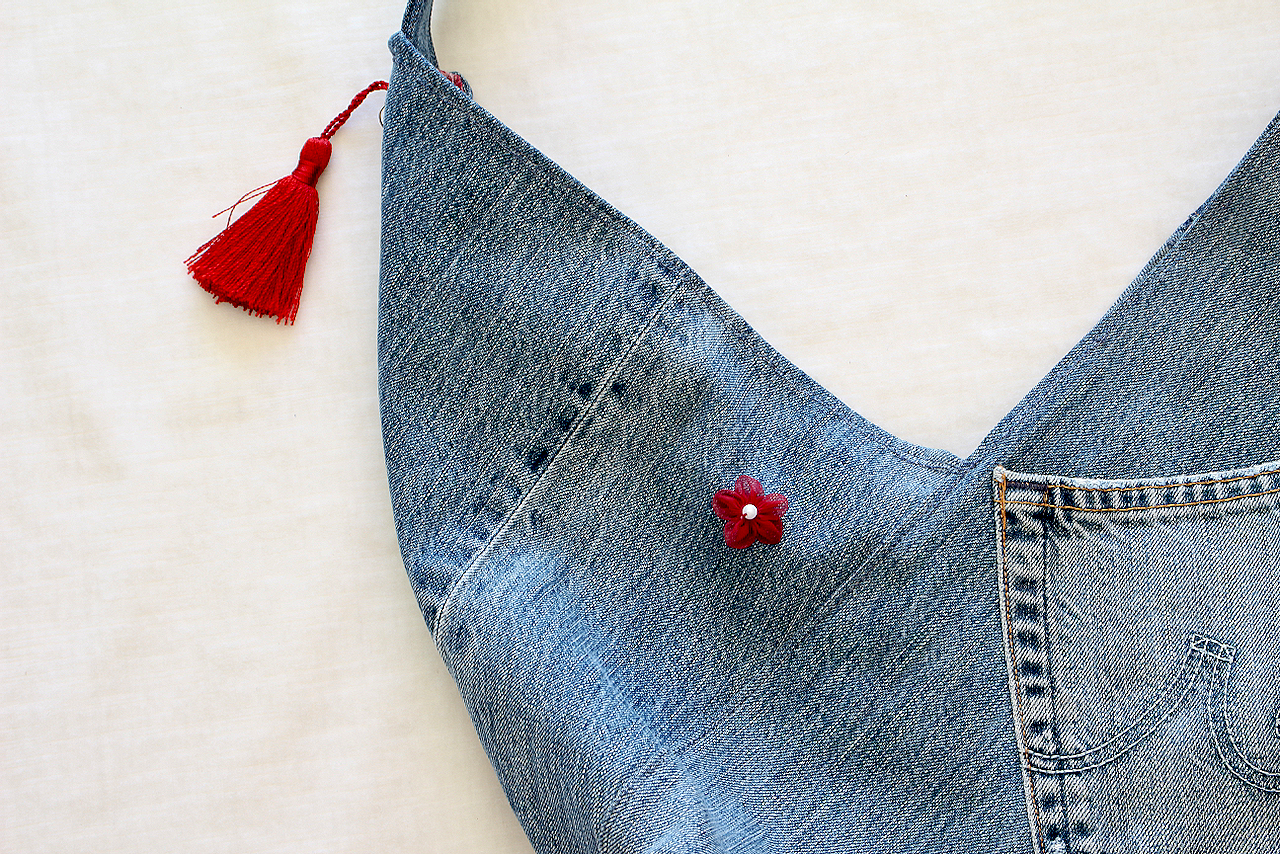 Handcrafted recycled denim hobo bag with red heart patch, red tassel, floral pearl pin, and vintage turquoise rhinestone pin, lined with floral turquoise and red recycled wool fabric.