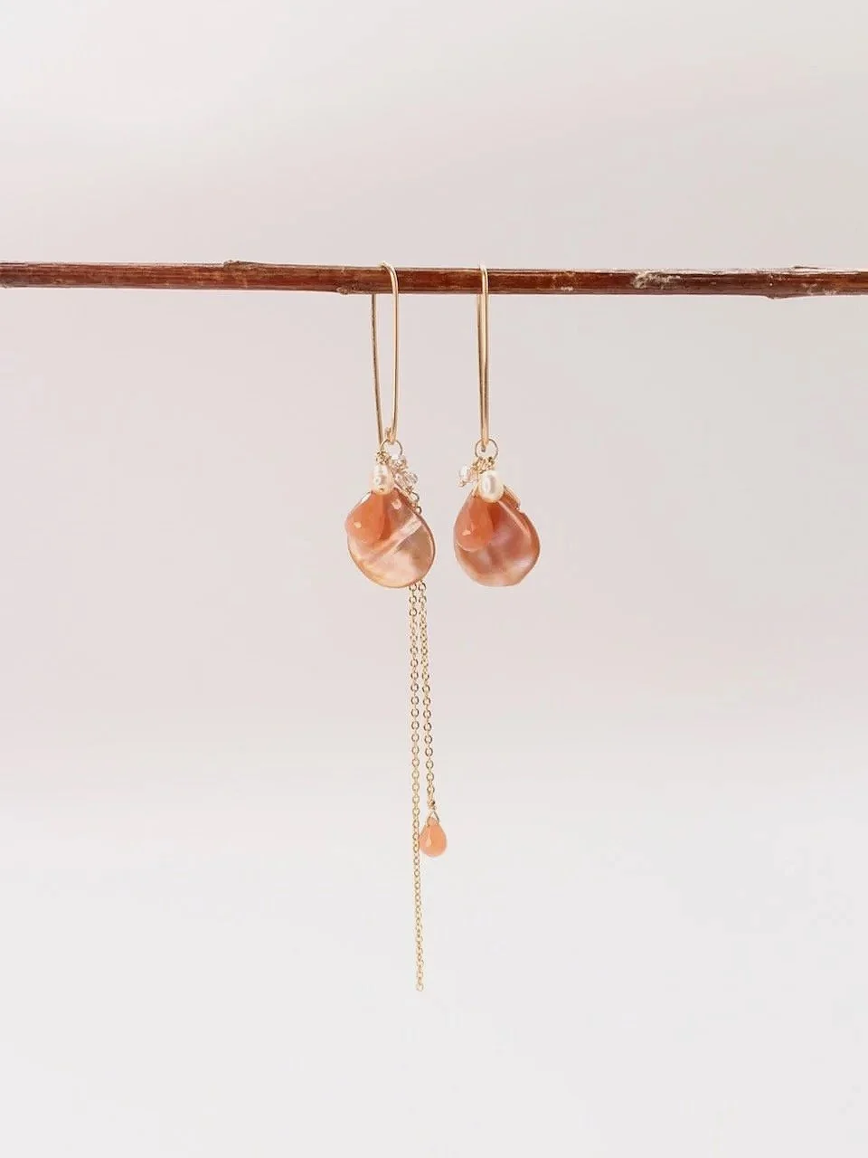 Mismatched dangle earrings with mother of pearl, pink moonstone, pearls, and crystal bead clusters on gold-filled ear wires.