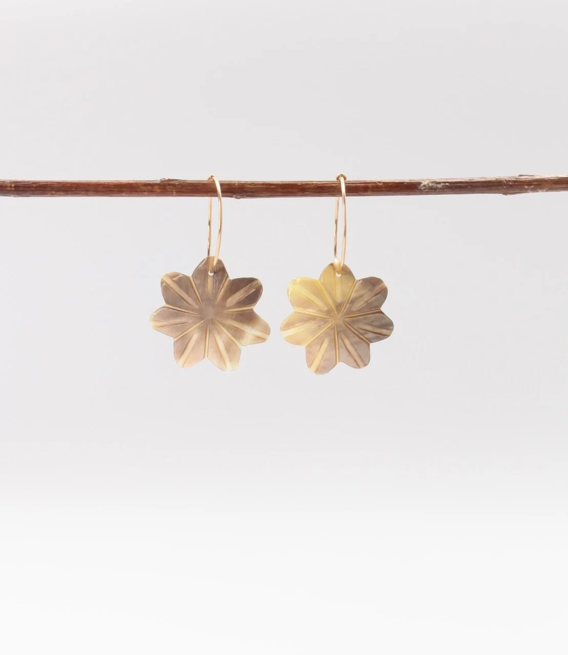 Gold filled hoop earrings featuring delicate mother of pearl flower charms.