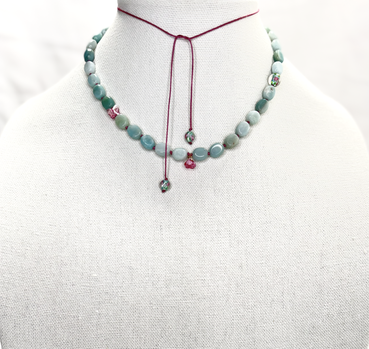 Amazonite necklace hand-knotted on pink Chinese cord with glass flowers, Swarovski crystal butterfly, and tassel with adjustable pull closure.