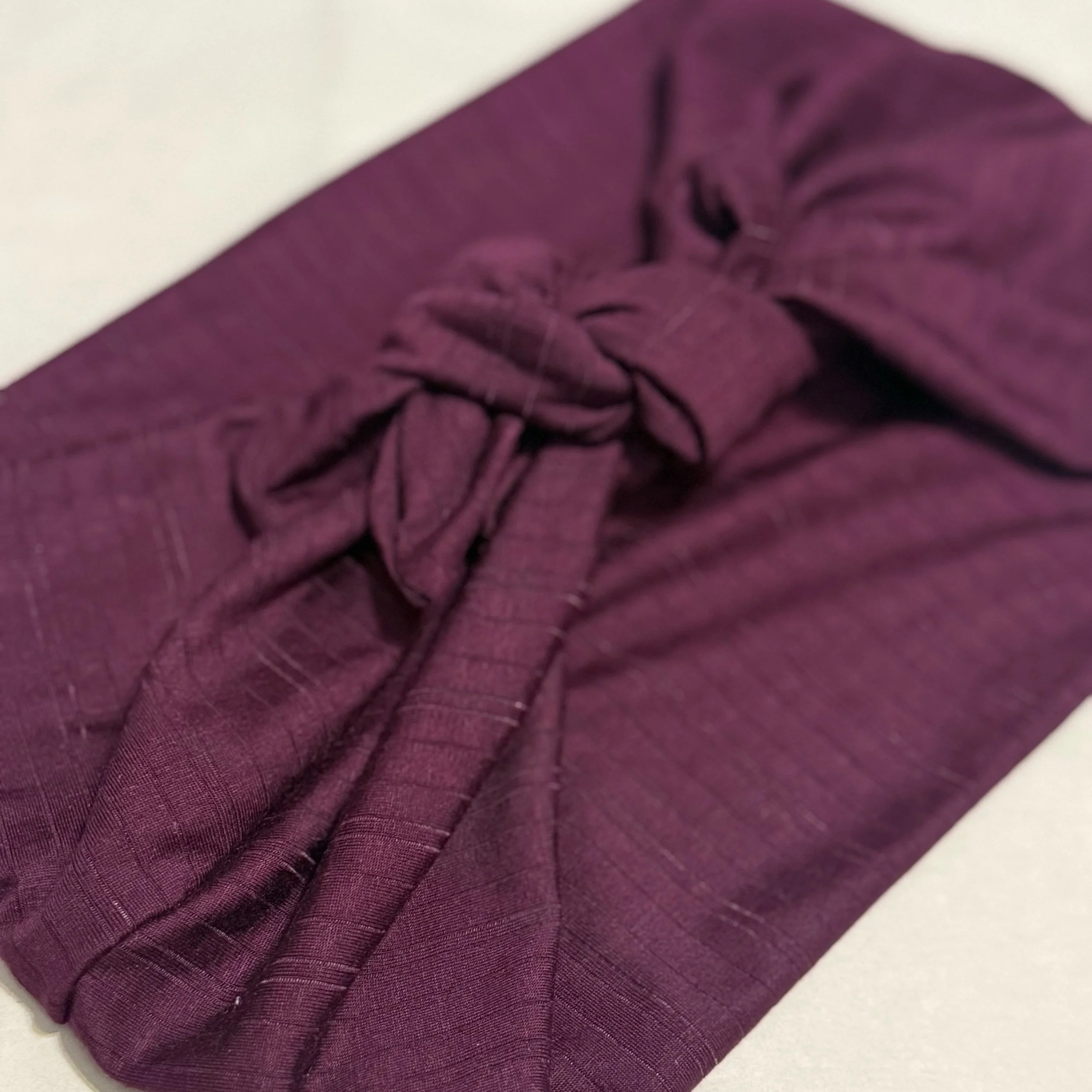 A plum purple with plum purple striped headband tide in a square knot