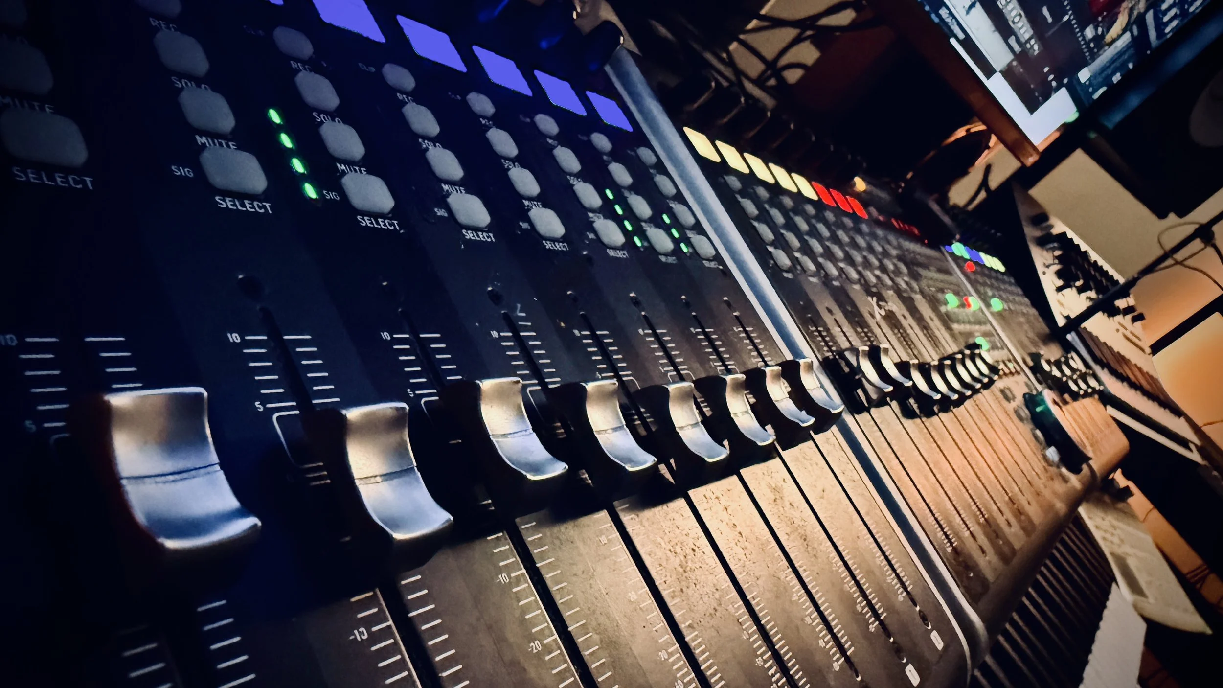 Close-up of a professional audio mixing console with faders, knobs, and digital controls.