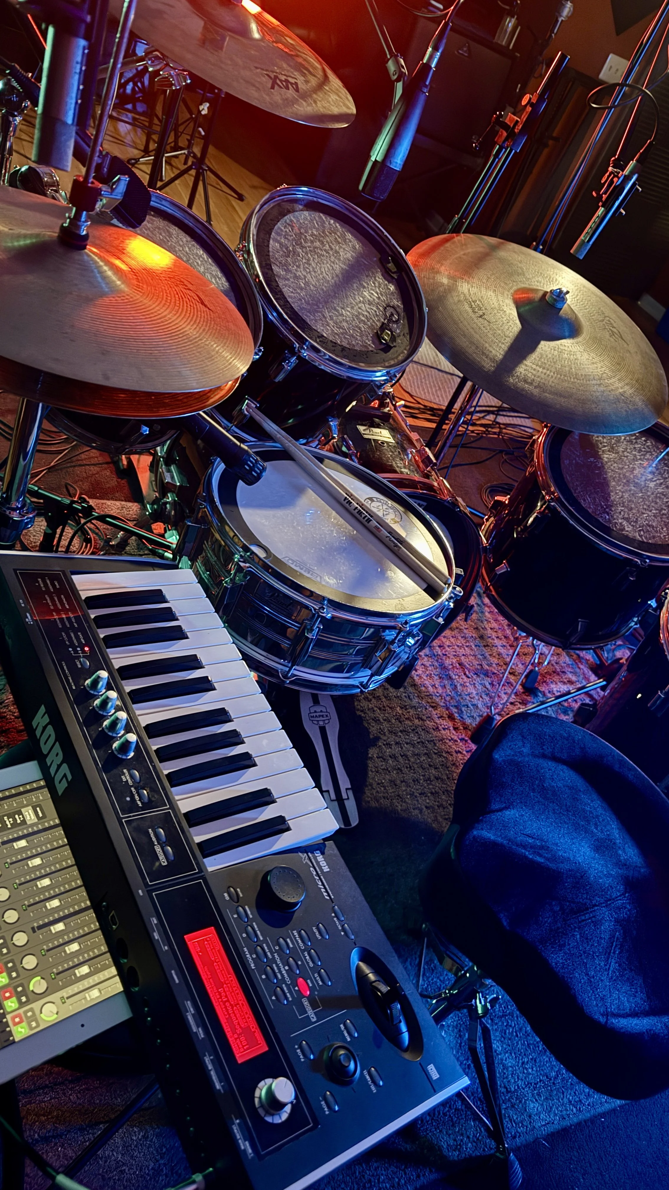 A drum set, electronic keyboard, and mixing console on a stage, ready for a musical performance.